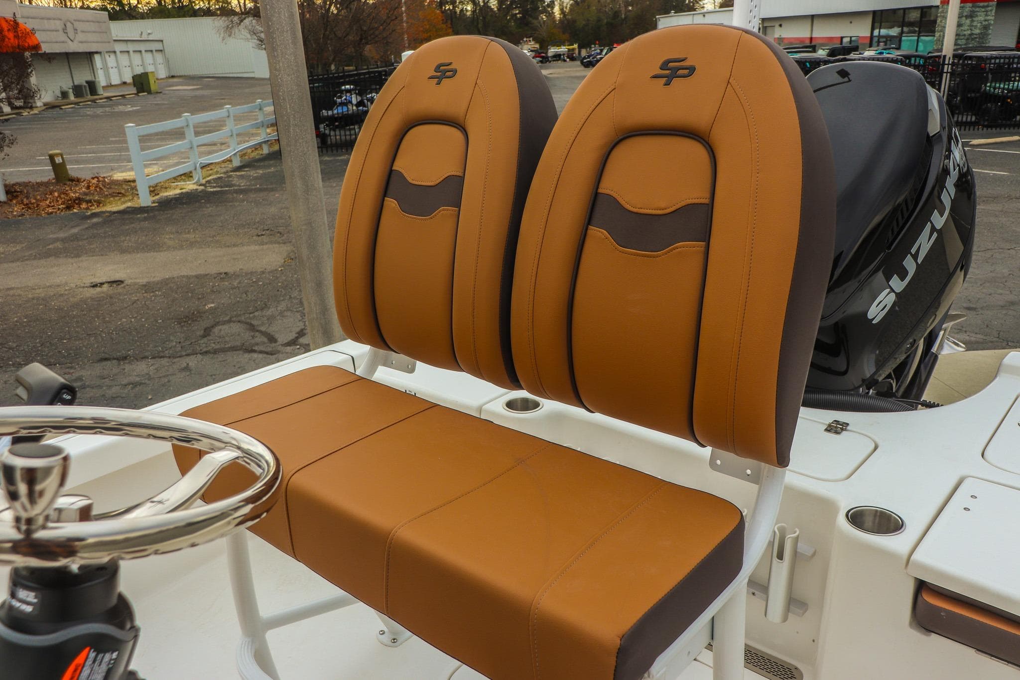 2026 Sea Pro 210 Bay boat seats with Suzuki engine in parking lot.