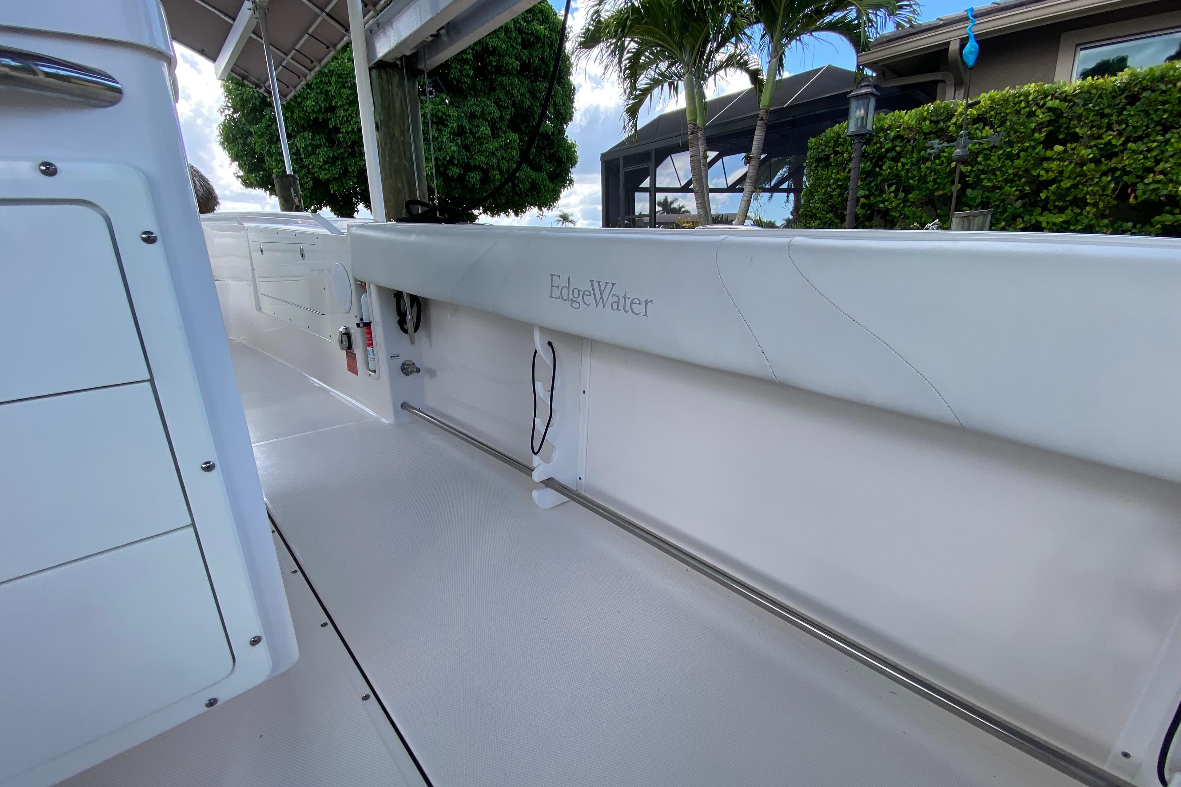 2015 Edgewater 320CC boat interior with white seating and lush greenery background.