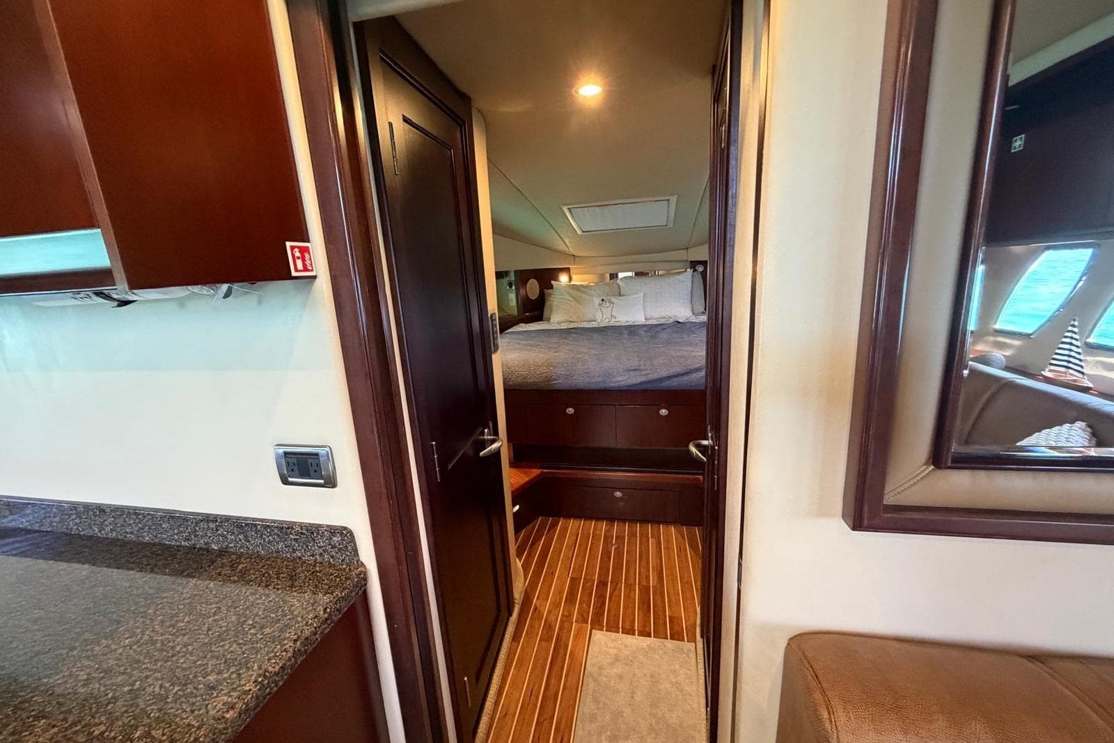 Interior of 2006 Sea Ray 480 Sundancer yacht, featuring a cozy bedroom and elegant wood finishes.
