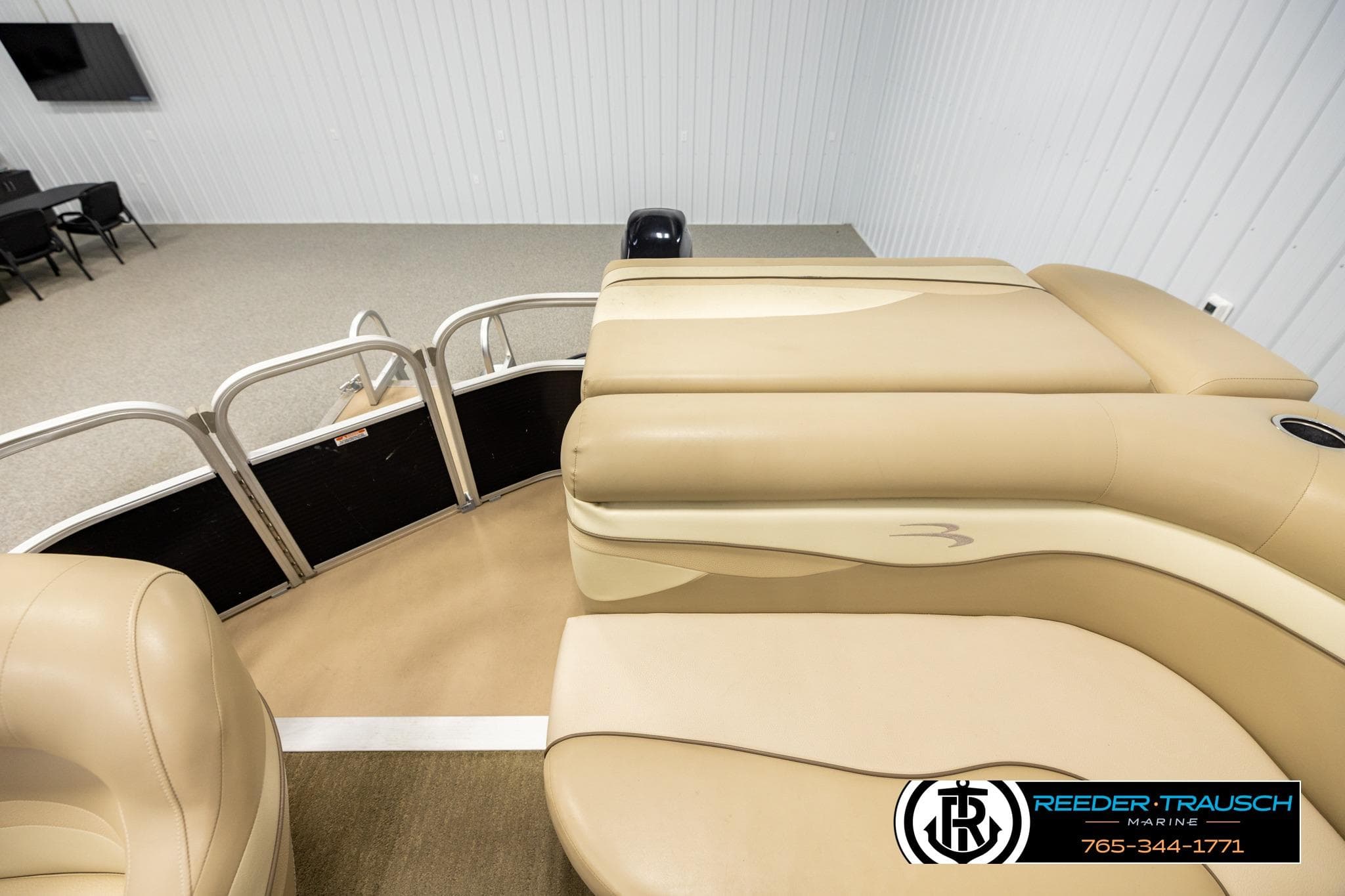 2013 Bennington 20 SLMX pontoon boat interior with beige seating in showroom.