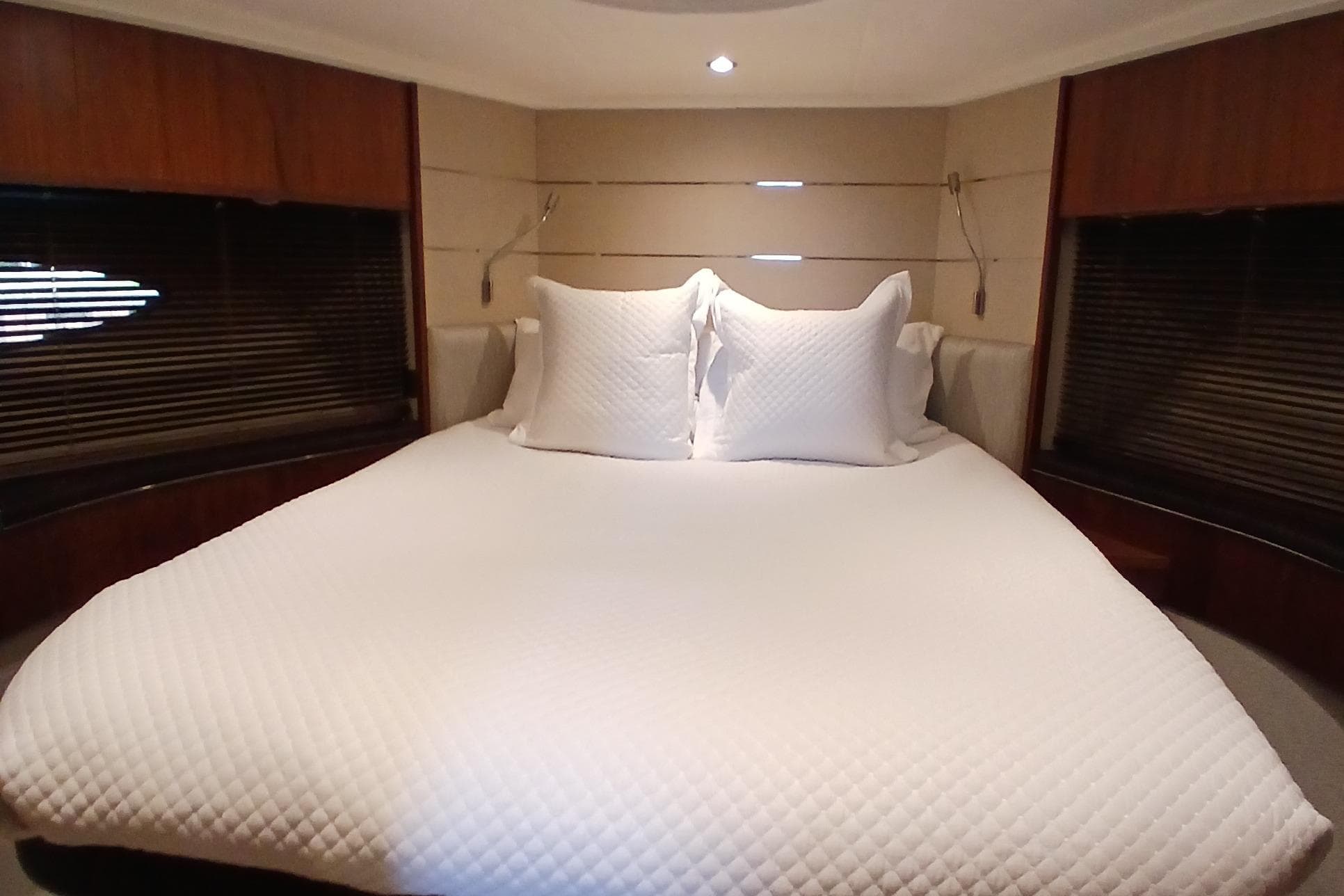 Luxurious bedroom interior of 2015 Princess V62-S yacht with elegant bedding.