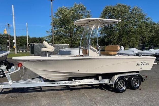 2024 Sea Chaser 21 LX boat on trailer, parked outdoors under clear blue sky.