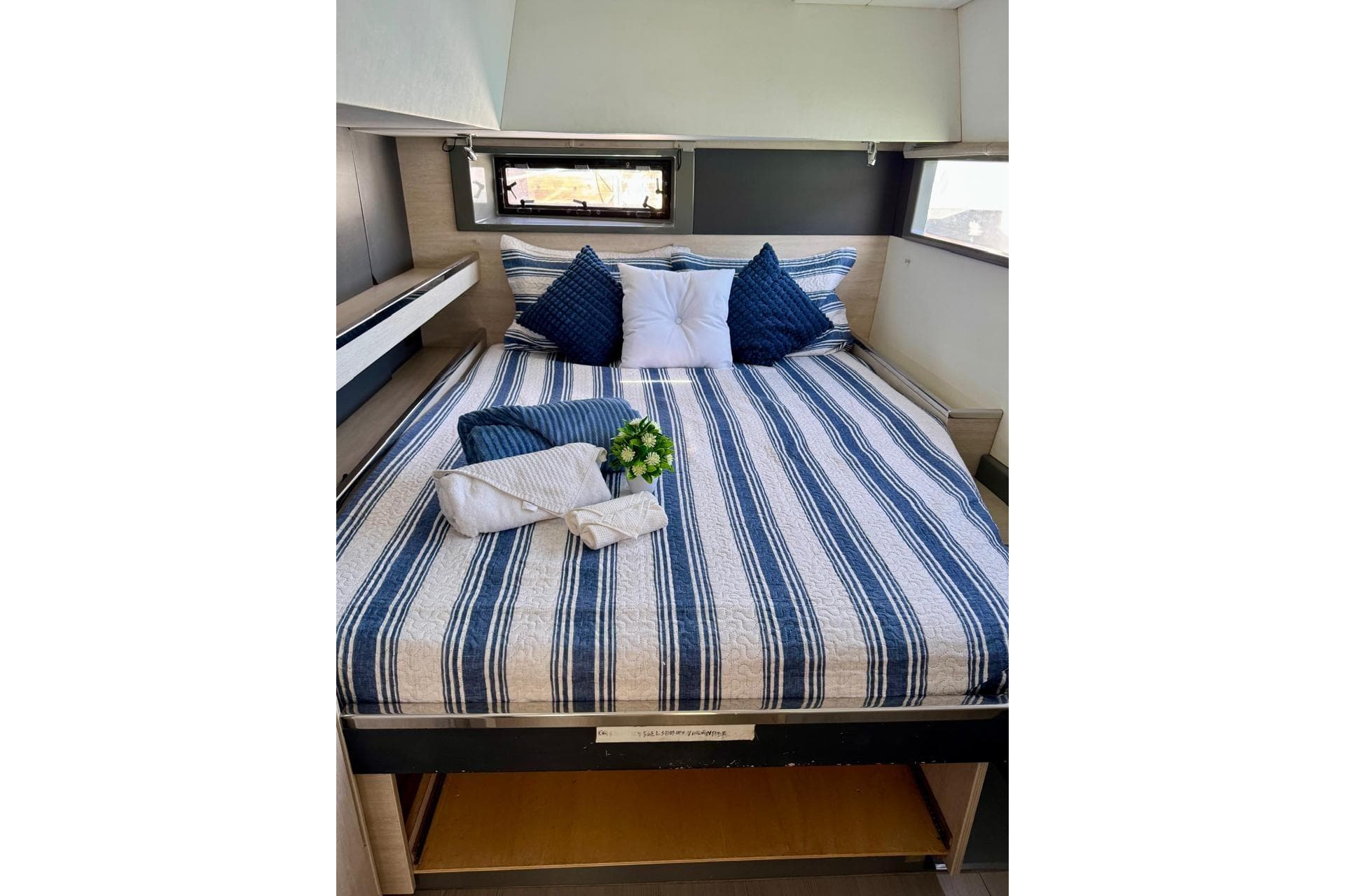 Cozy cabin bed in 2017 Leopard 45 yacht with striped bedding and decorative pillows.