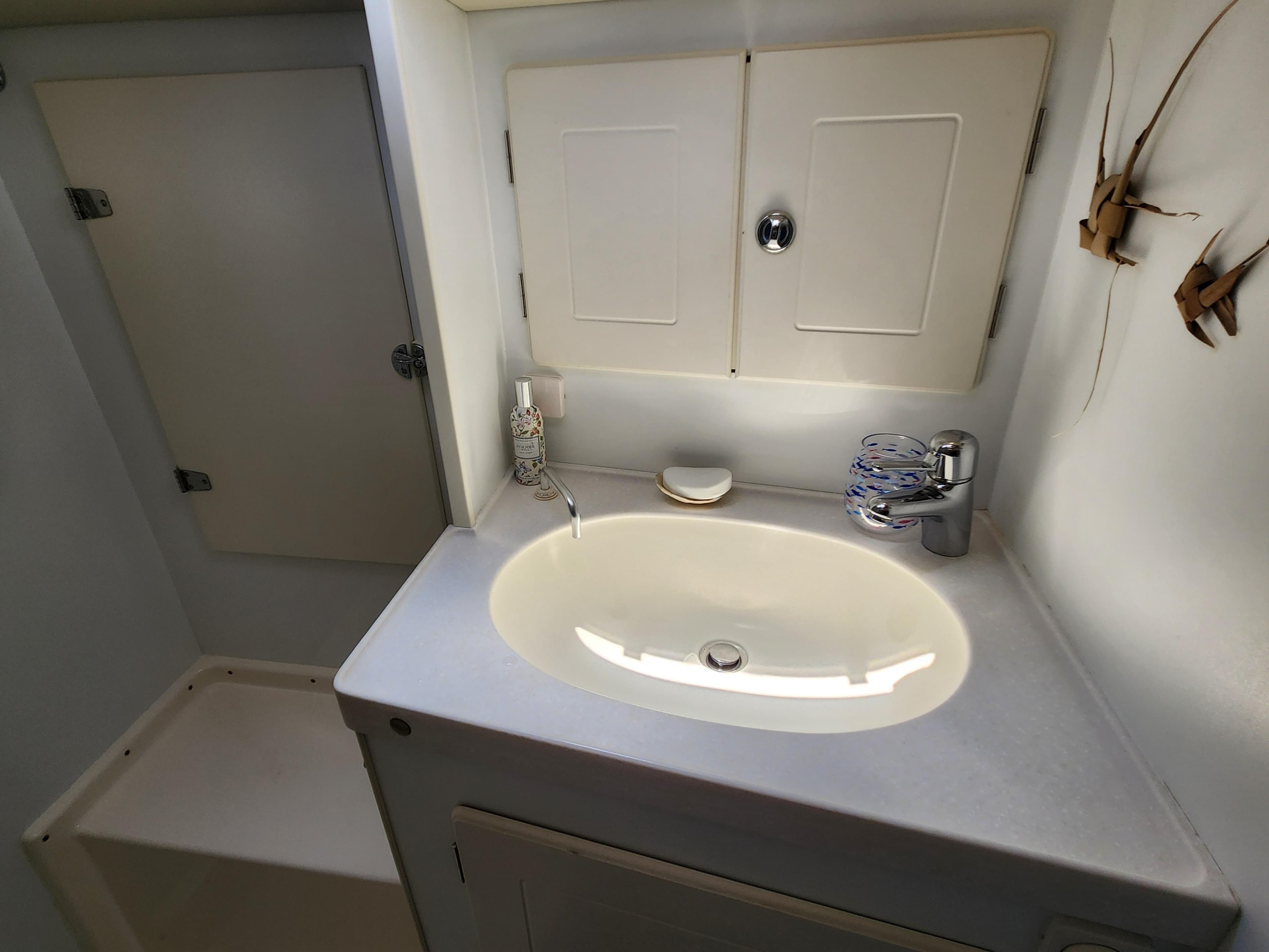 Hallberg-Rassy 48 (2006) yacht bathroom with sink, faucet, and storage cabinets.