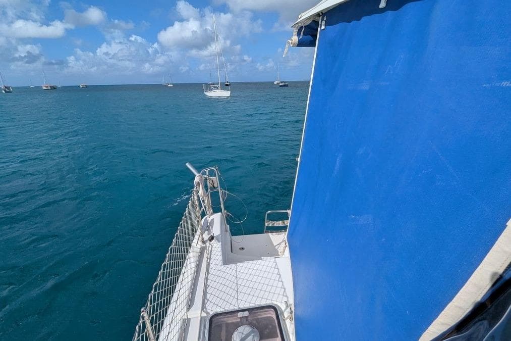 Sailing on a 2008 Lagoon 420 catamaran with blue canopy, ocean view.