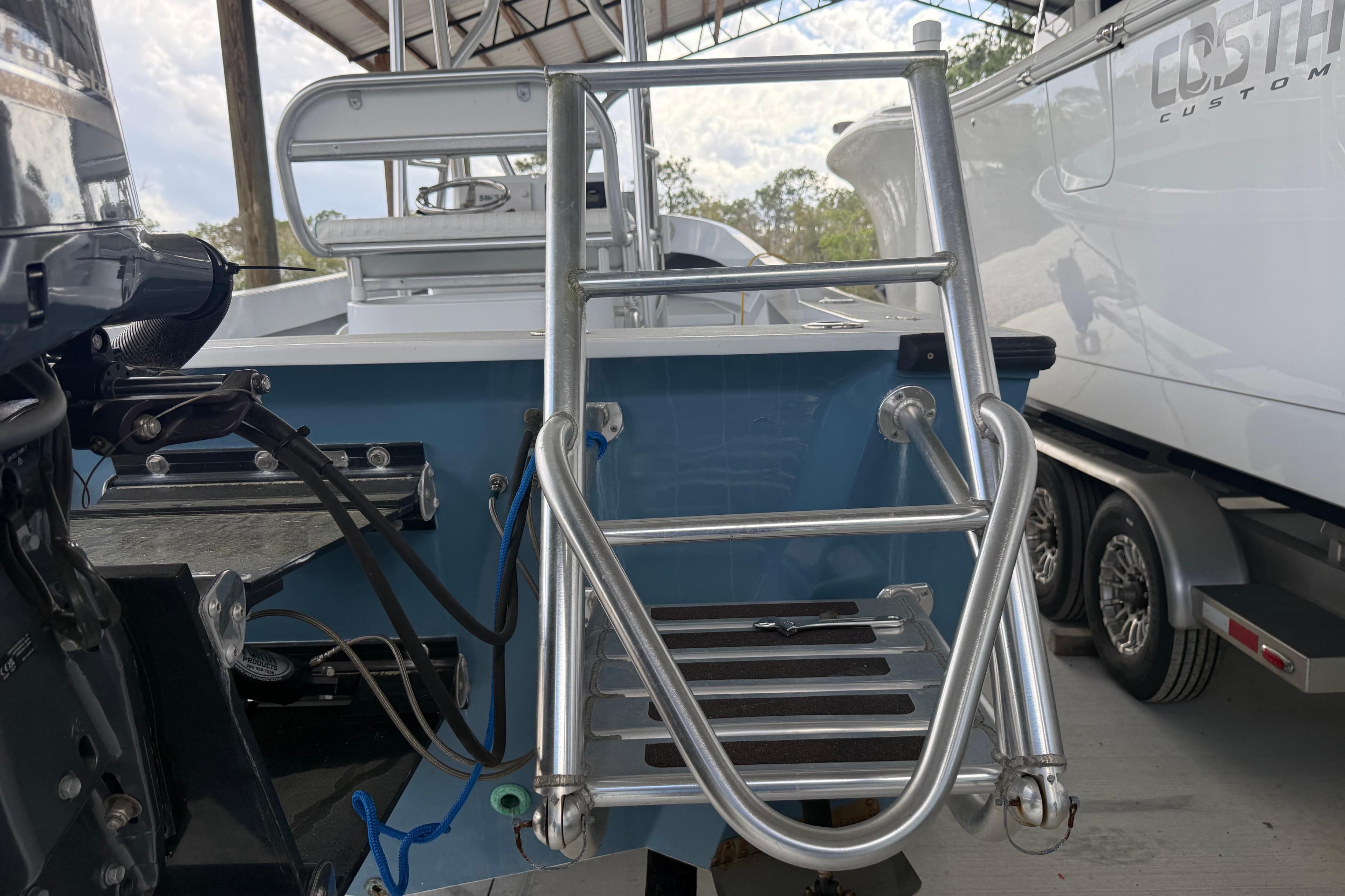 1974 Aquasport 2400 Center Console boat with metal ladder and motor, docked indoors.