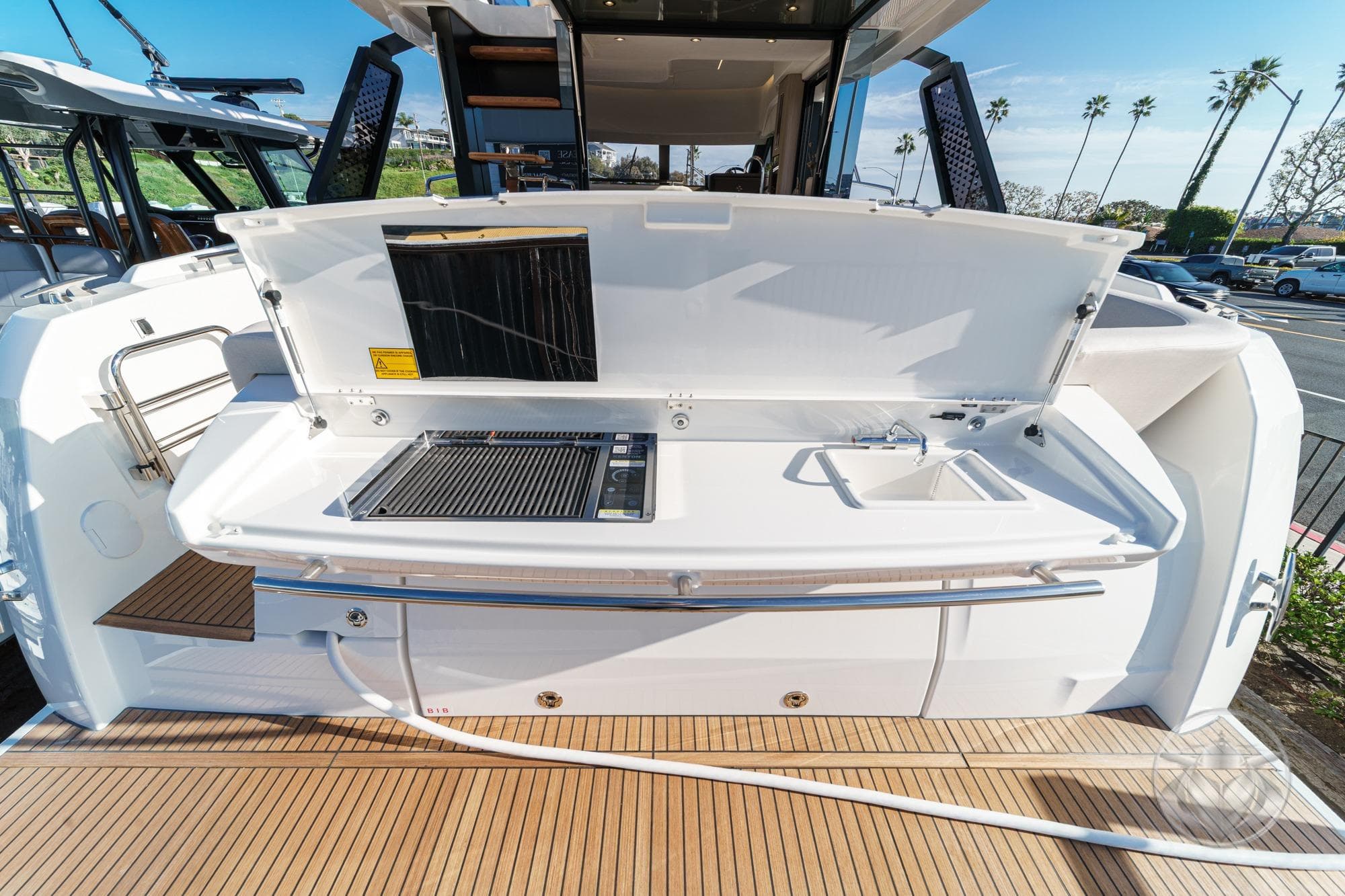 Outdoor kitchen on 2026 Prestige F4.3 yacht with grill and sink, docked under clear skies.