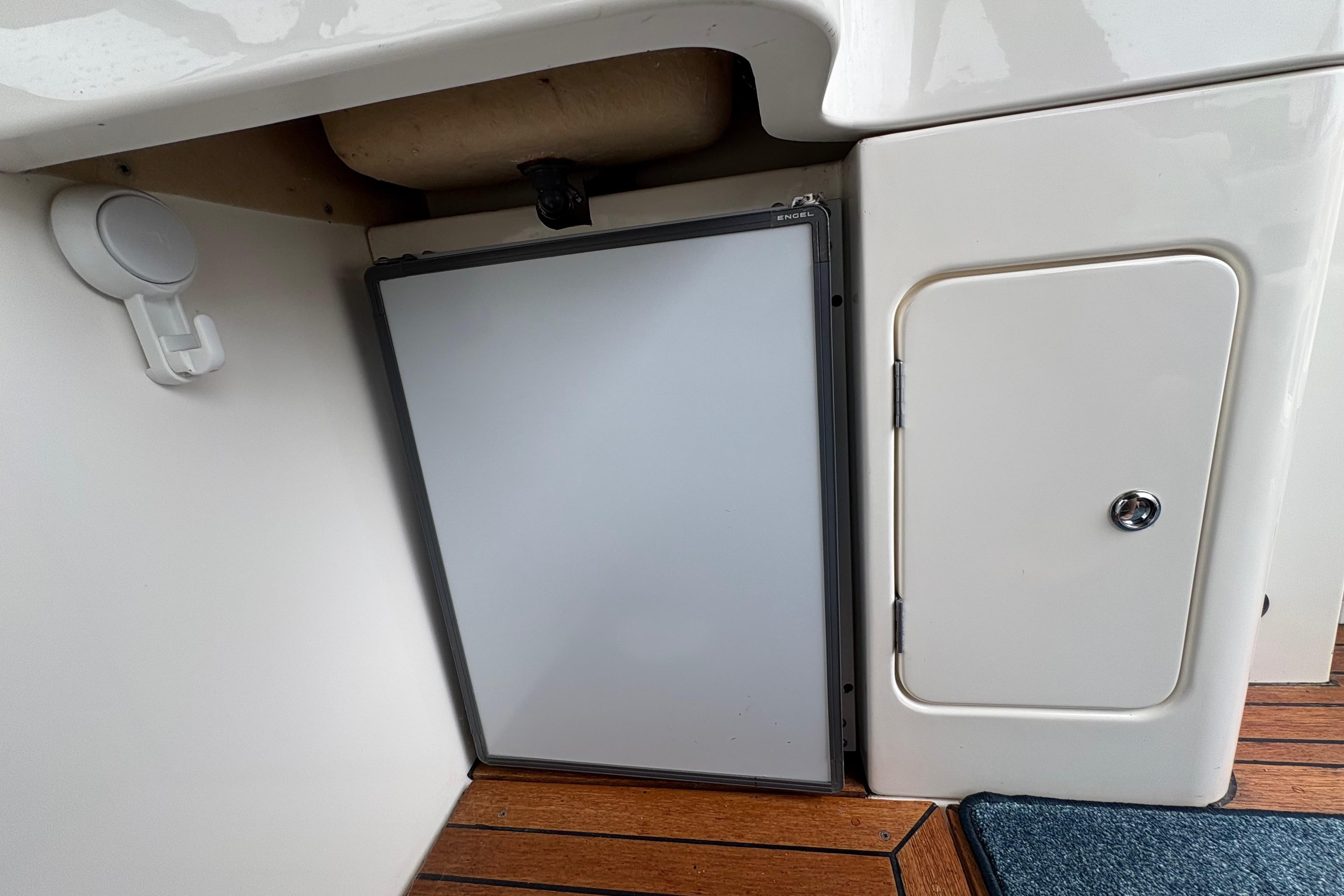 Interior of a 2002 Capriole 900 boat showing a compact fridge and storage compartment.