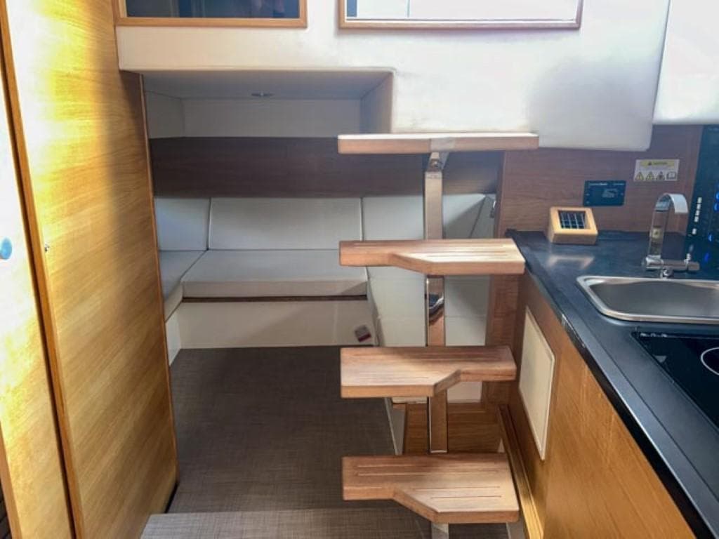 Interior of 2023 De Antonio Yachts D42 Open, featuring modern wooden stairs and compact kitchen.
