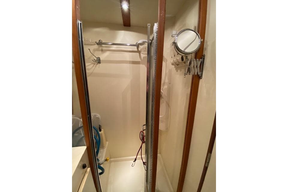 1999 Mainship 350 Trawler bathroom with shower, mirror, and wooden accents.