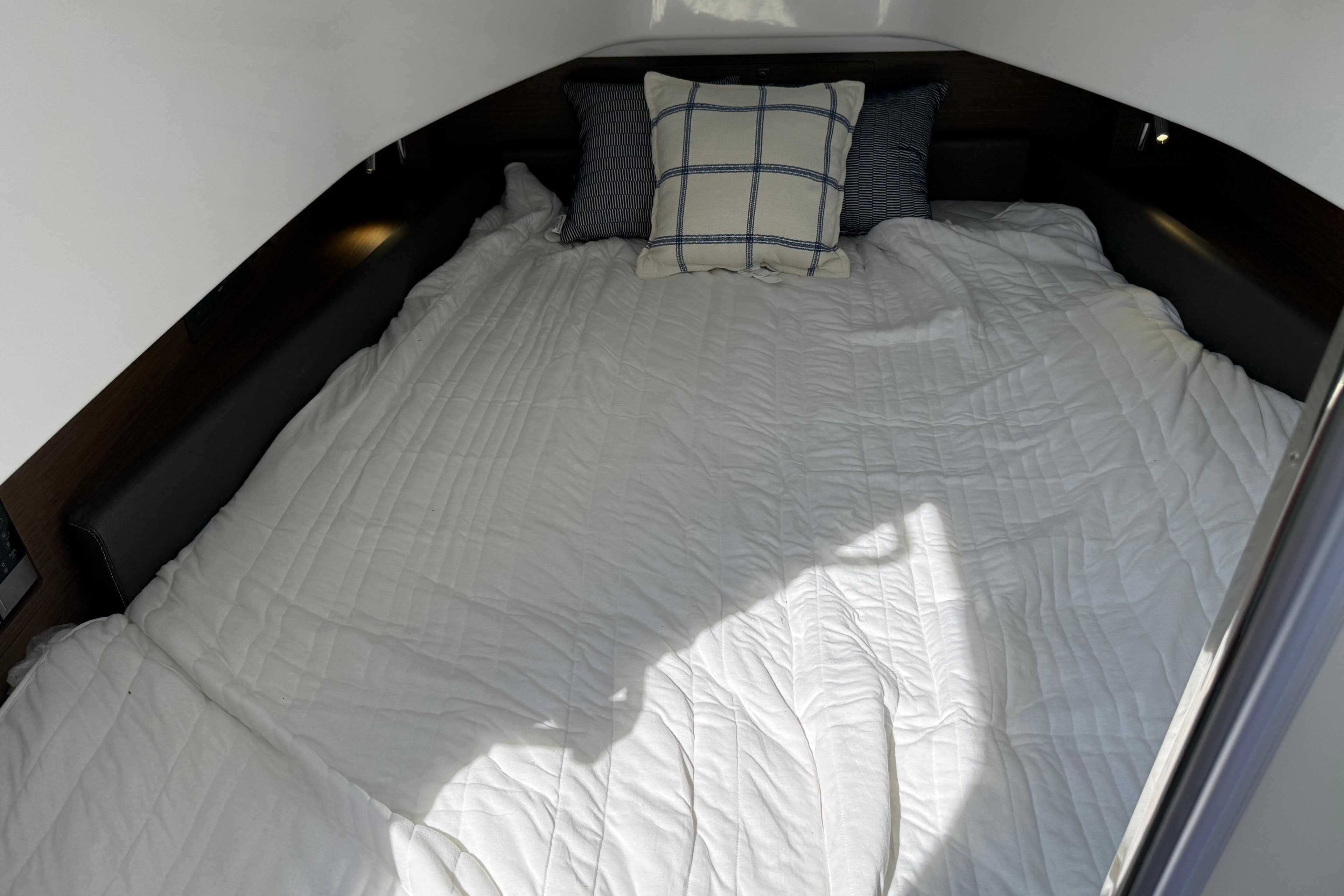 Cozy cabin bed in 2026 Wellcraft 38 T-Top boat with pillows and white bedding.