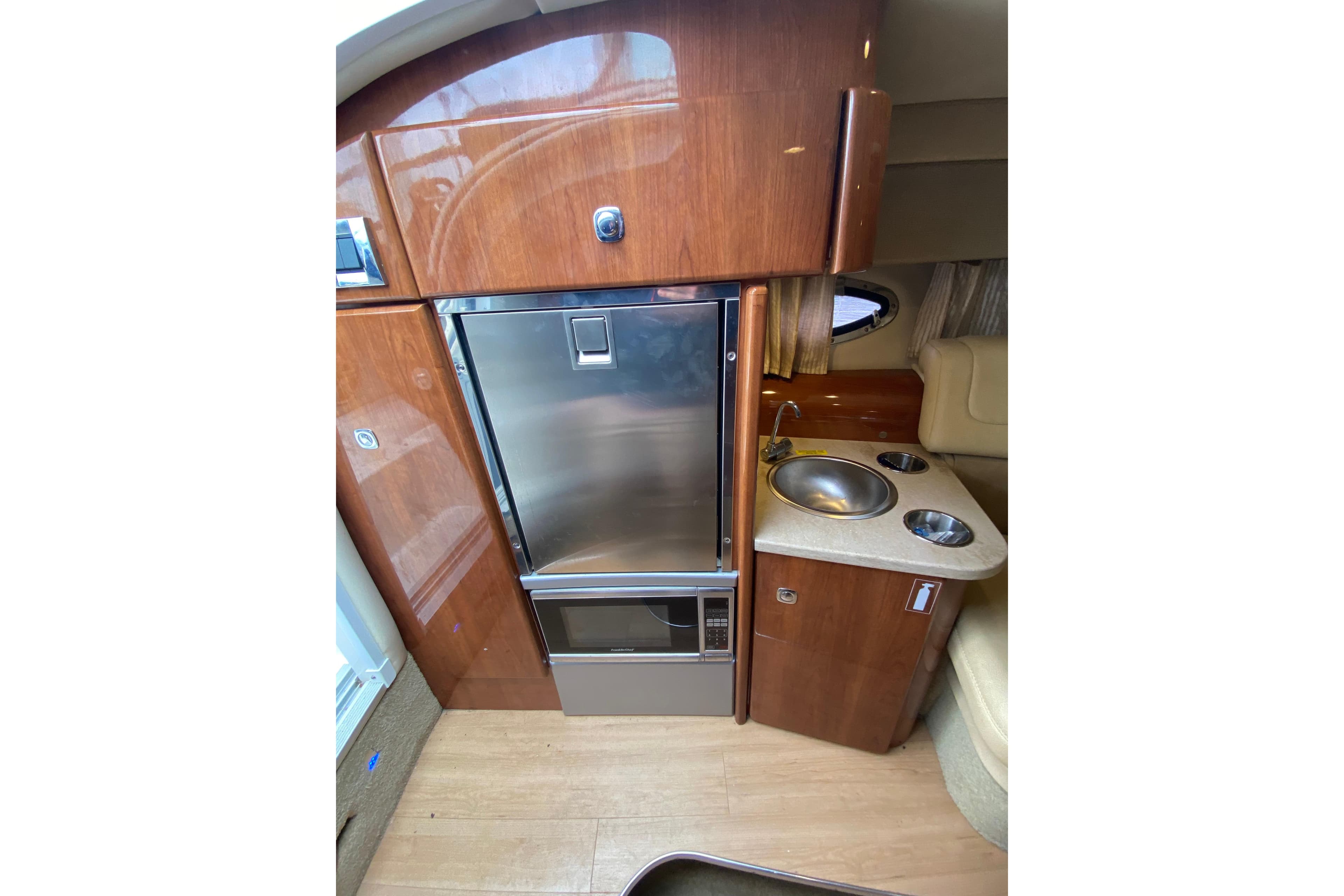 2015 Formula 310 Sun Sport interior with kitchenette, featuring wood cabinetry and stainless steel appliances.