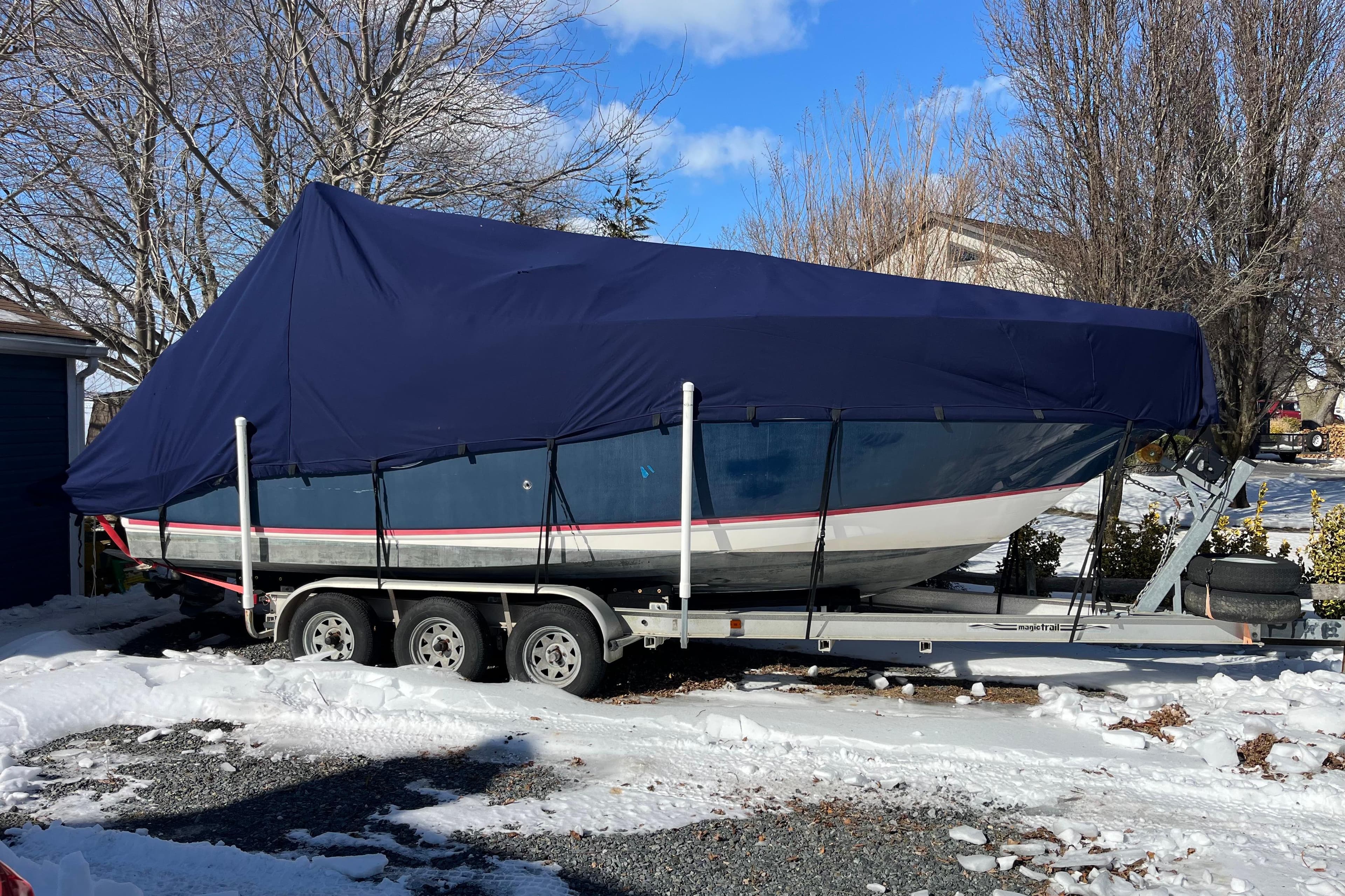 2006 Regal Commodore 2665 boat covered on trailer in snowy driveway.