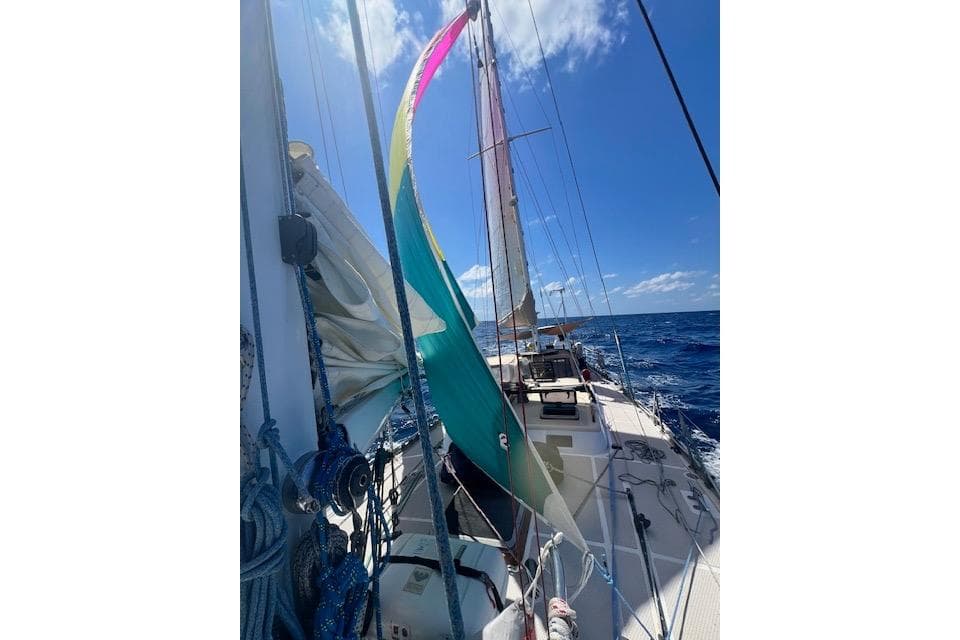 Sailing on a 1985 Robert Clark Ketch with colorful sails against a clear blue sky.