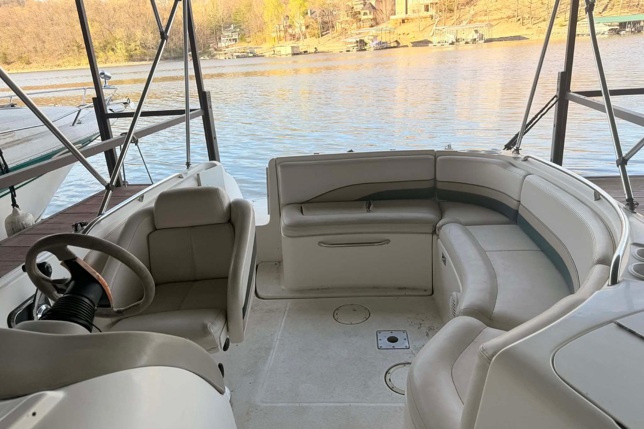 1998 Chaparral Sunesta 252 boat interior with seating and steering wheel by the water.