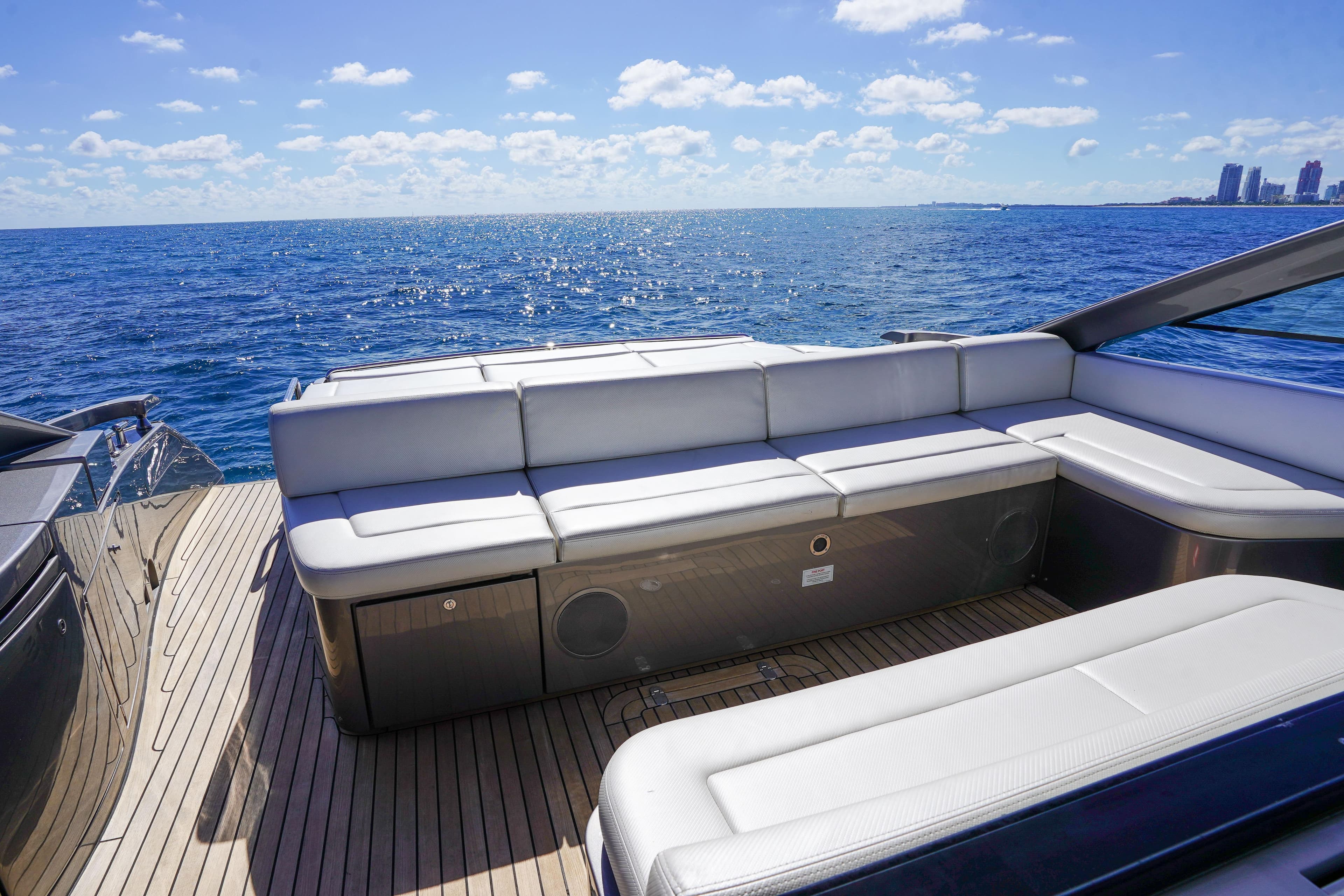 Luxurious 2019 Pershing 5x yacht deck with white seating, overlooking the ocean.