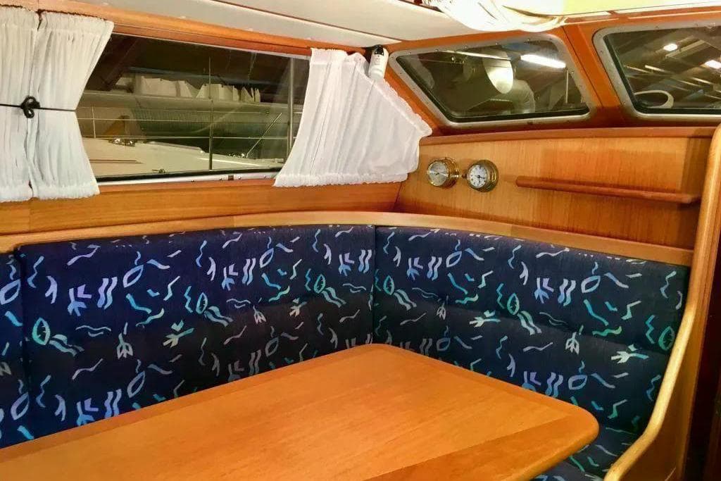 Cozy interior of 1998 Nordship 35 DS sailboat with patterned seating and wooden table.