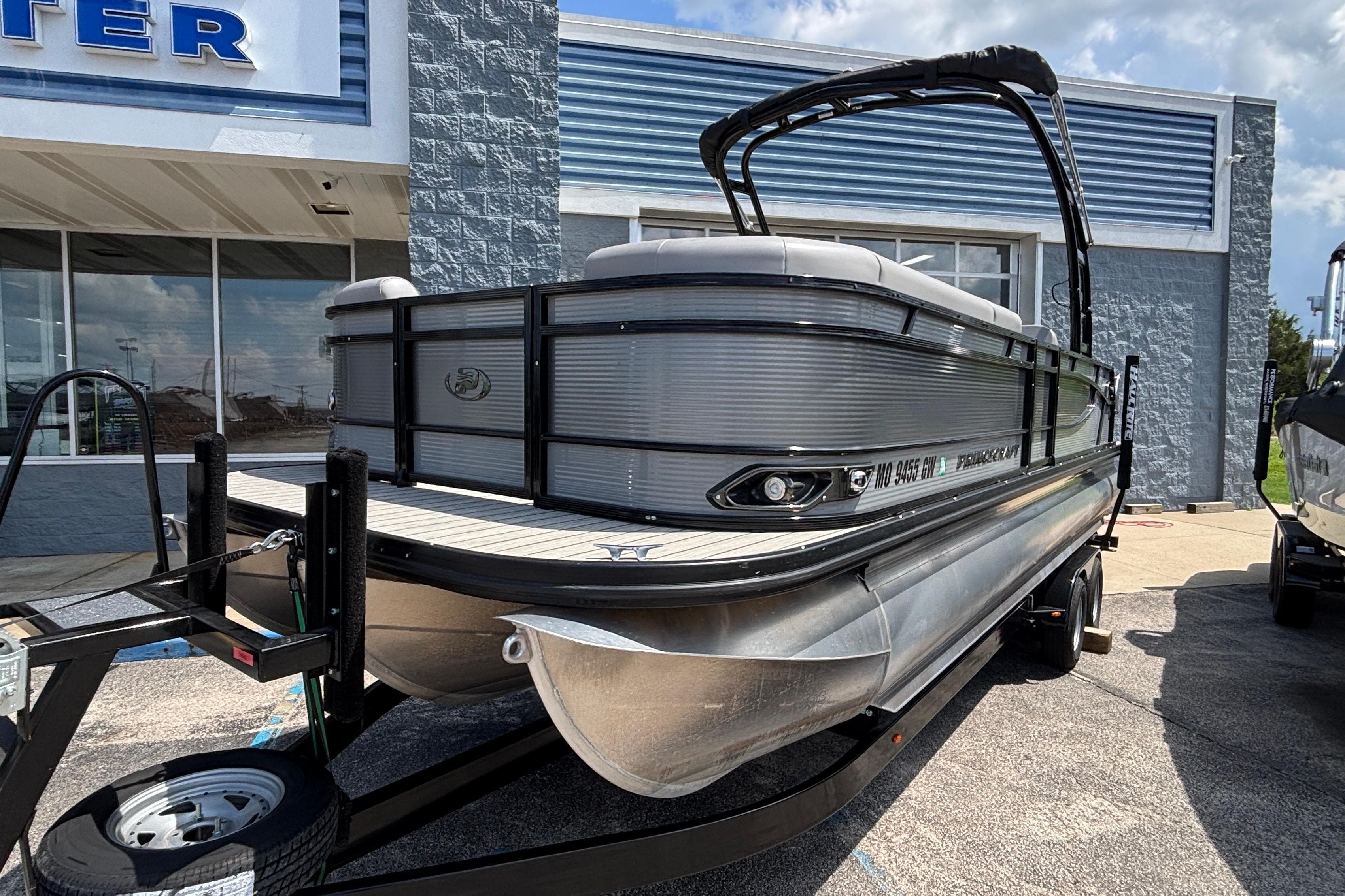 2023 Princecraft Quorum 25 RL pontoon boat on trailer outside dealership.