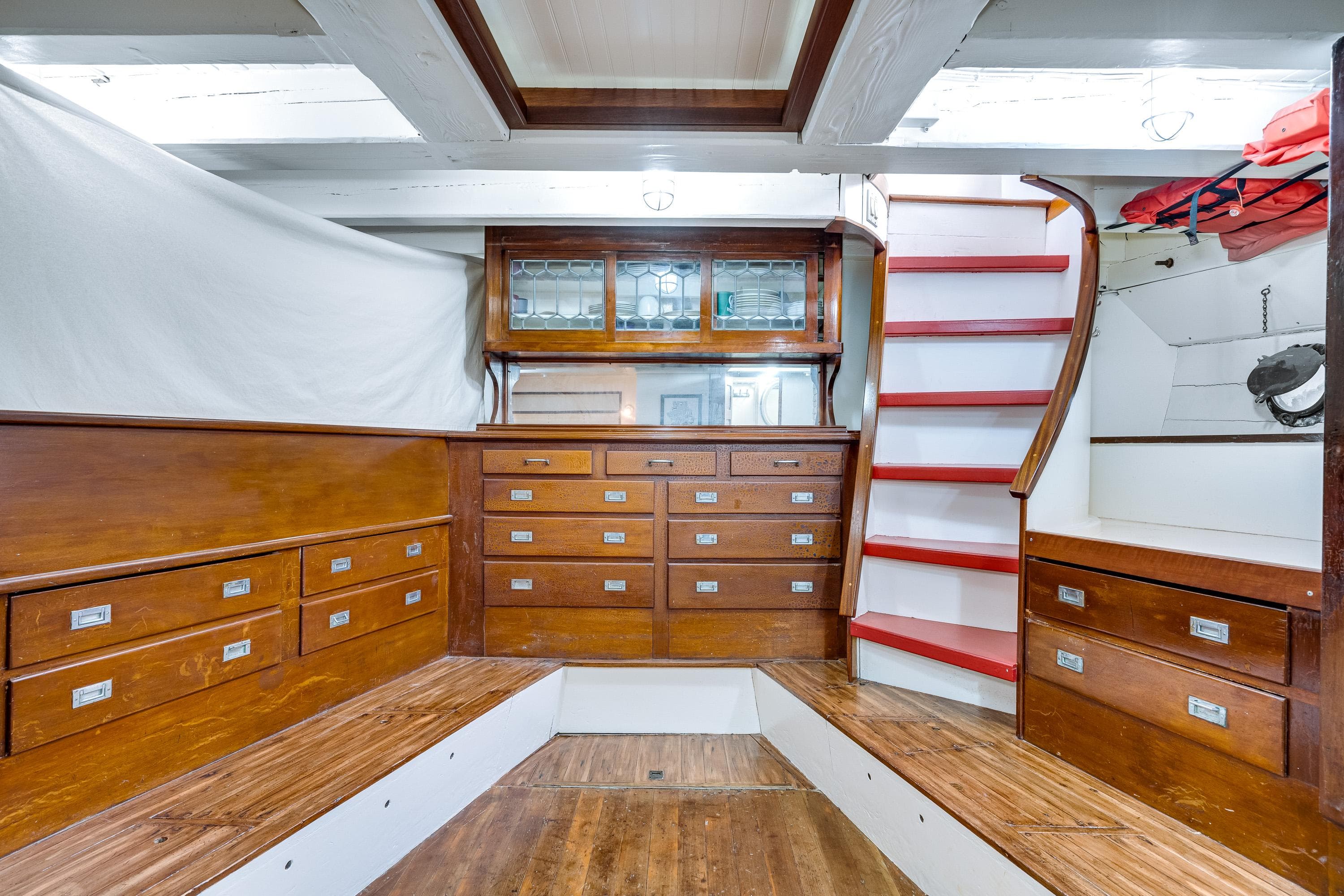 Interior of 1941 Custom Sagstad Fantail boat with wooden cabinetry and red-accented stairs.