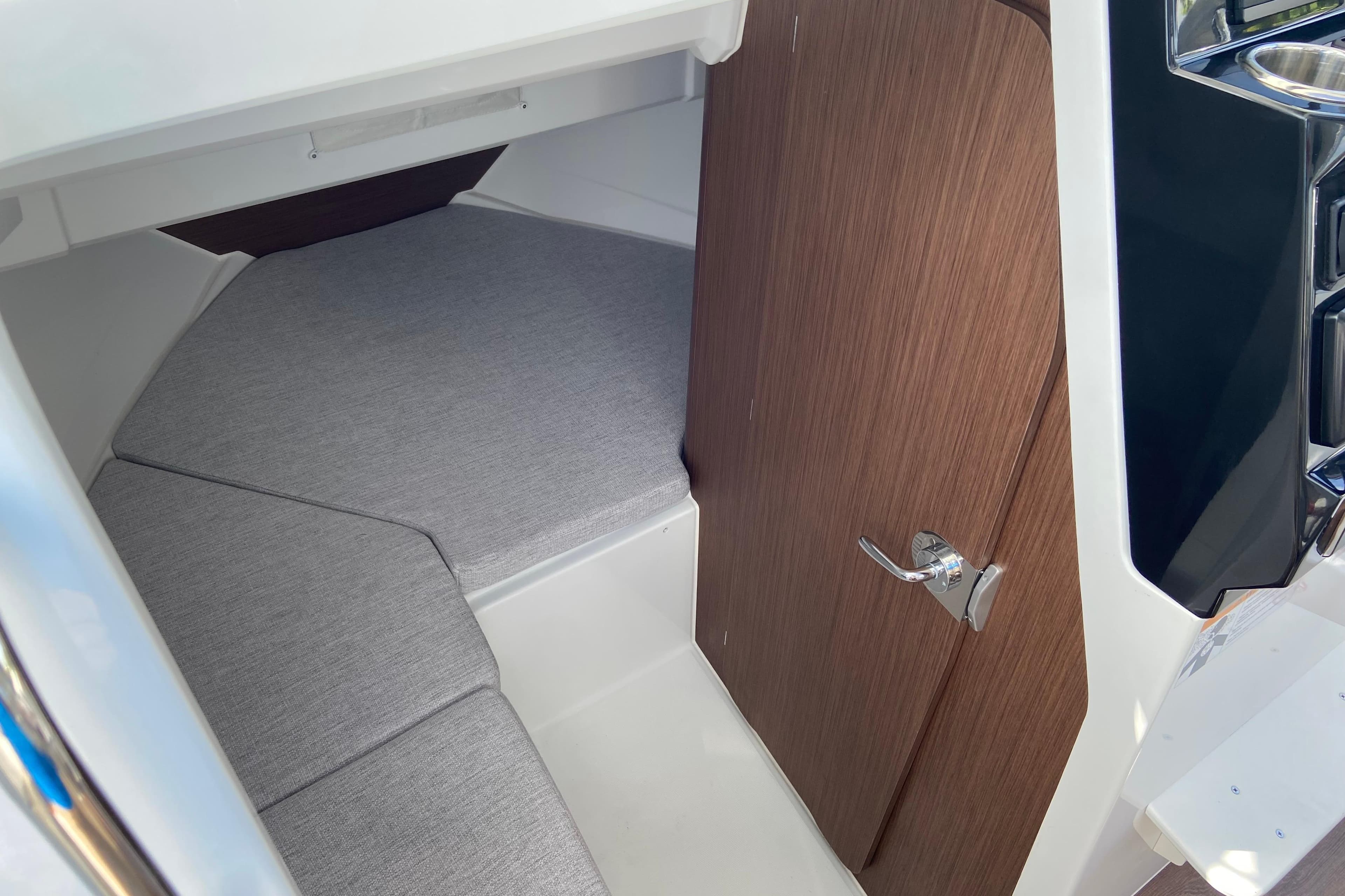 2026 Jeanneau NC Sport 795 Series 2 cabin interior with wooden door and cushioned seating.