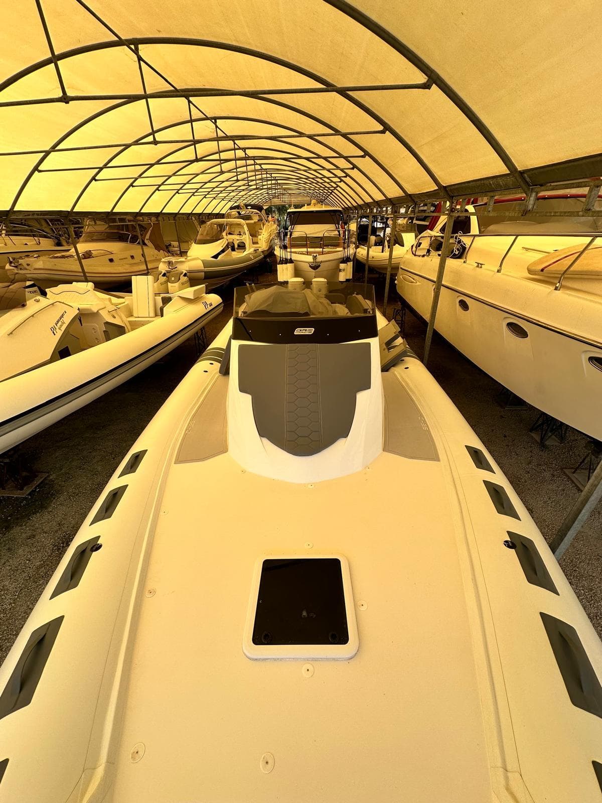 2023 Oromarine C35 boat under a canopy, surrounded by other boats in storage.