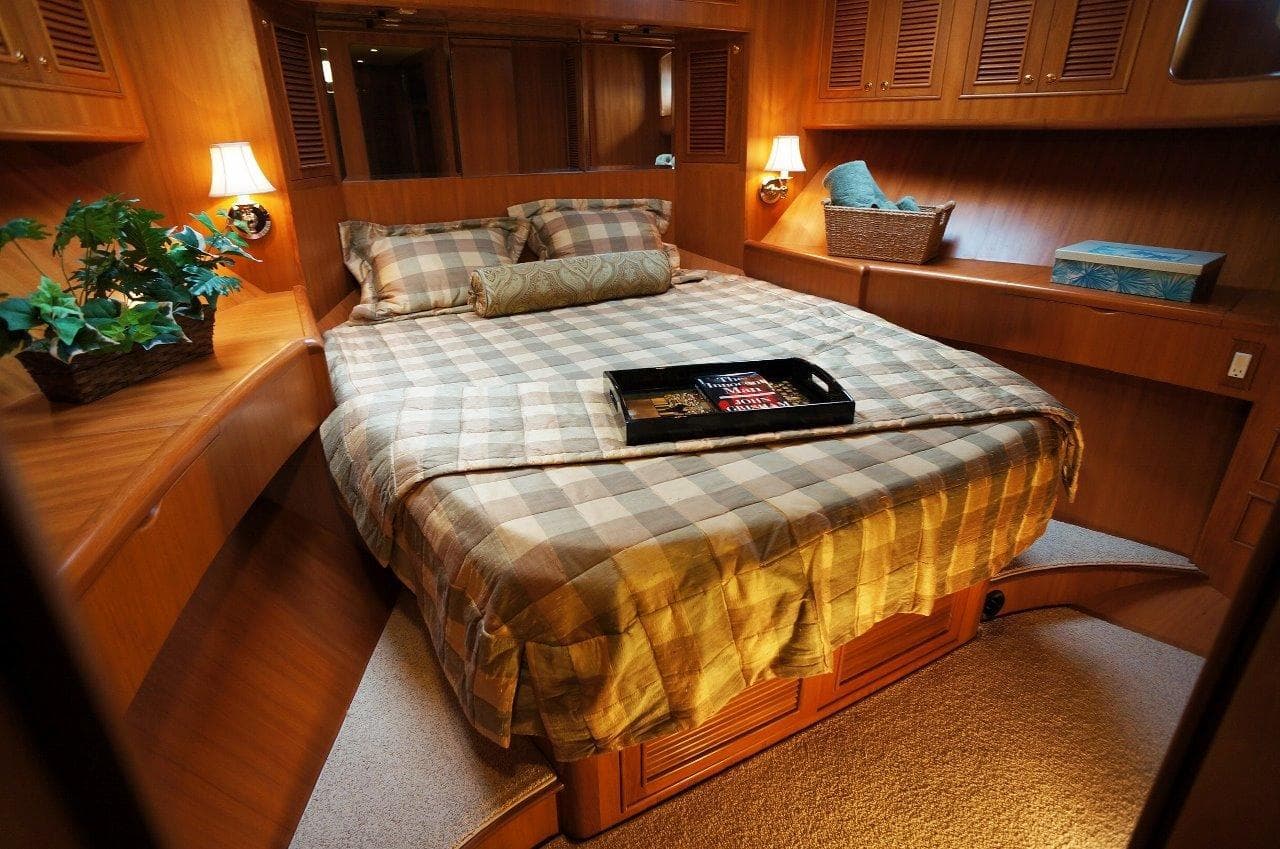 Luxurious bedroom interior of 2027 Legend Boats 630 Flybridge with cozy bedding and warm lighting.