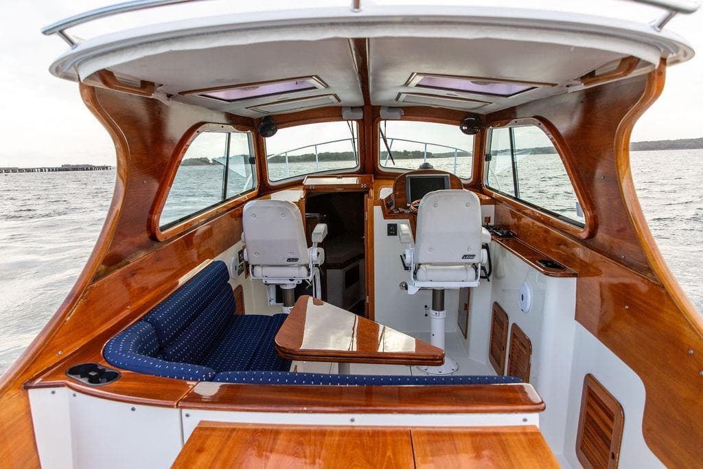 2004 Hinckley Picnic Boat EP interior with polished wood and blue seating on the water.
