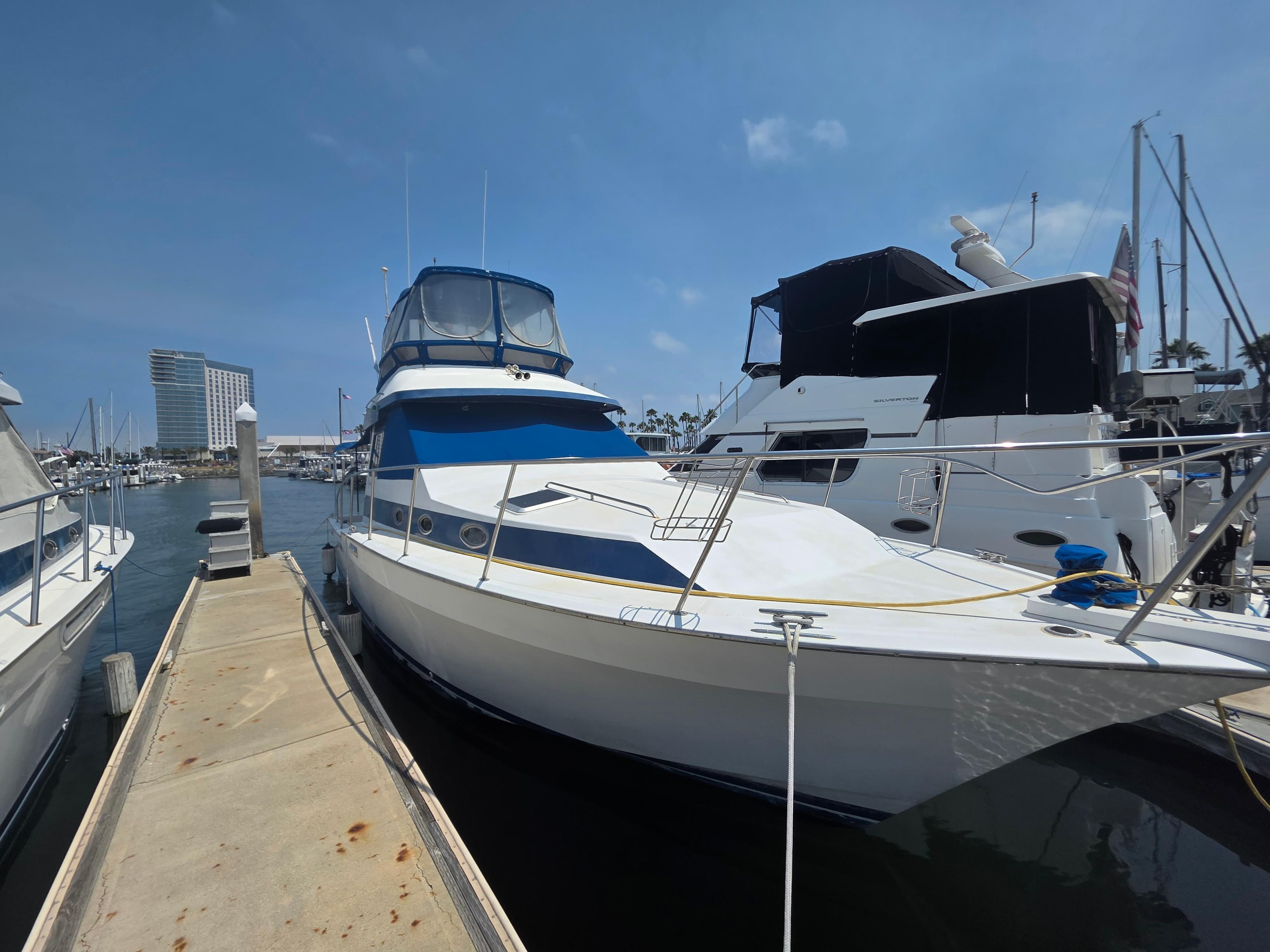 1988 Mediterranean 38 Convertible yacht docked at marina under clear blue sky.