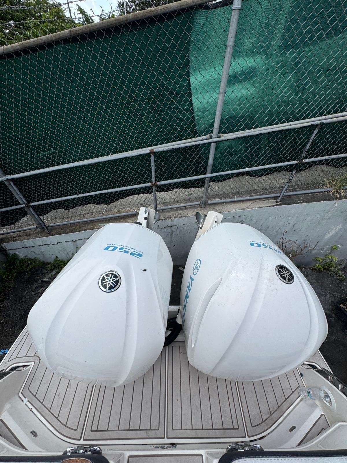 2018 Regal 29 OBX with twin Yamaha 250 outboard engines, docked near a green fence.