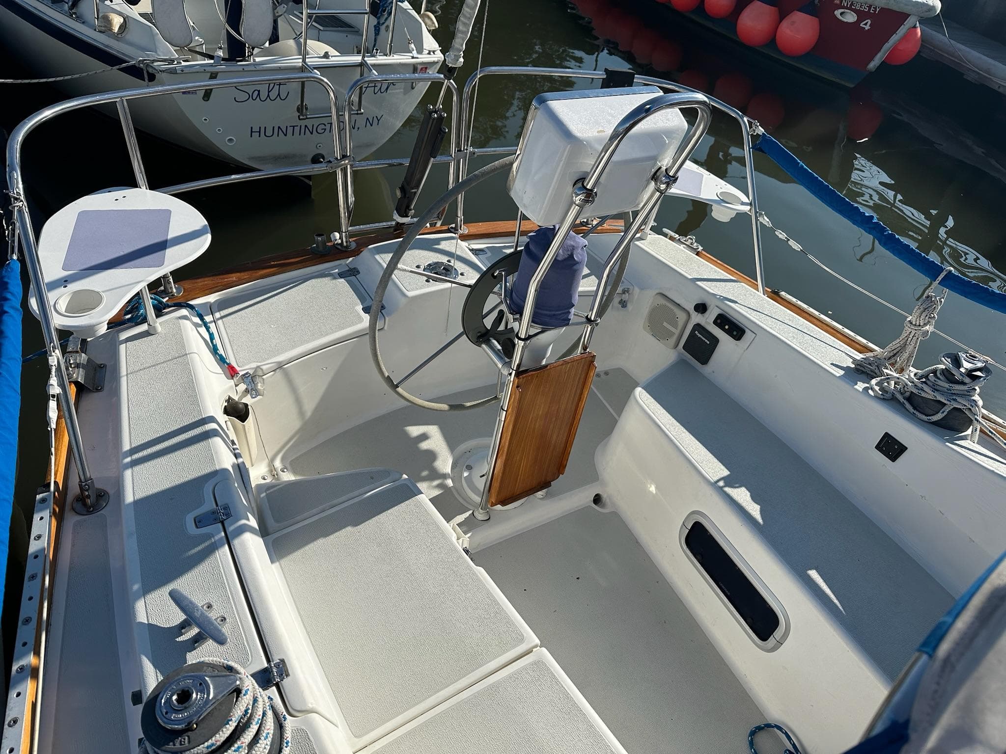 1988 Tartan 31 sailboat cockpit with steering wheel and seating, docked in marina.