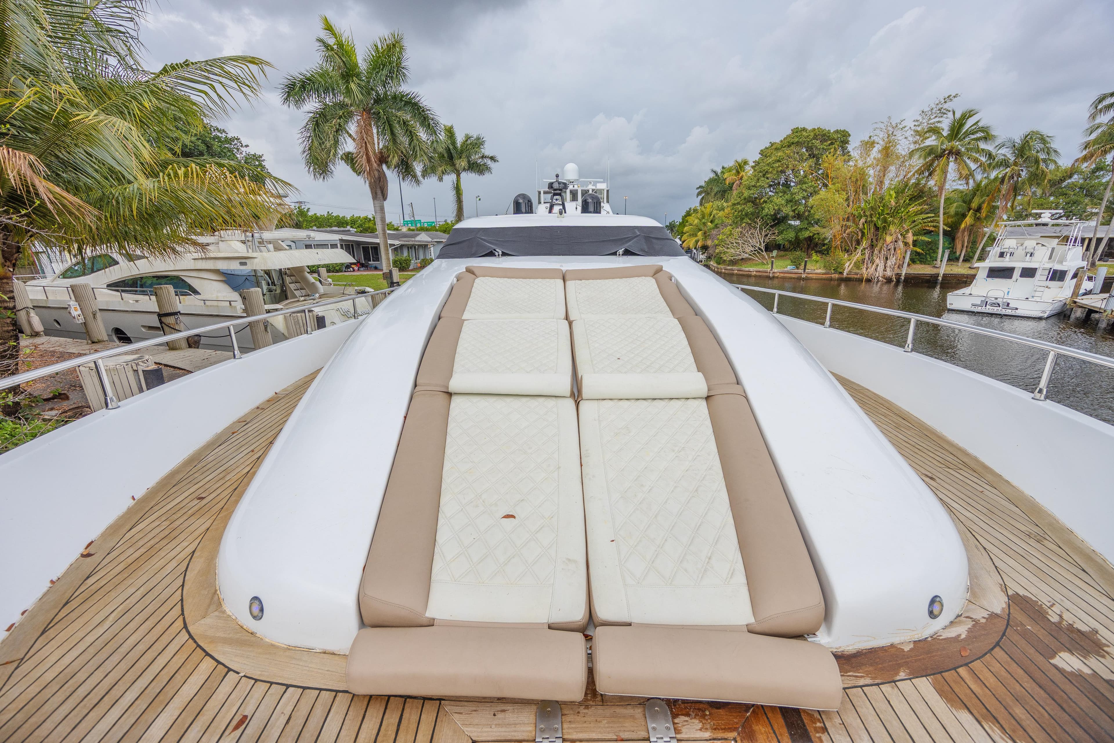 Luxury Tecnomar 90 yacht deck with sun loungers, surrounded by tropical scenery, 2007 model.