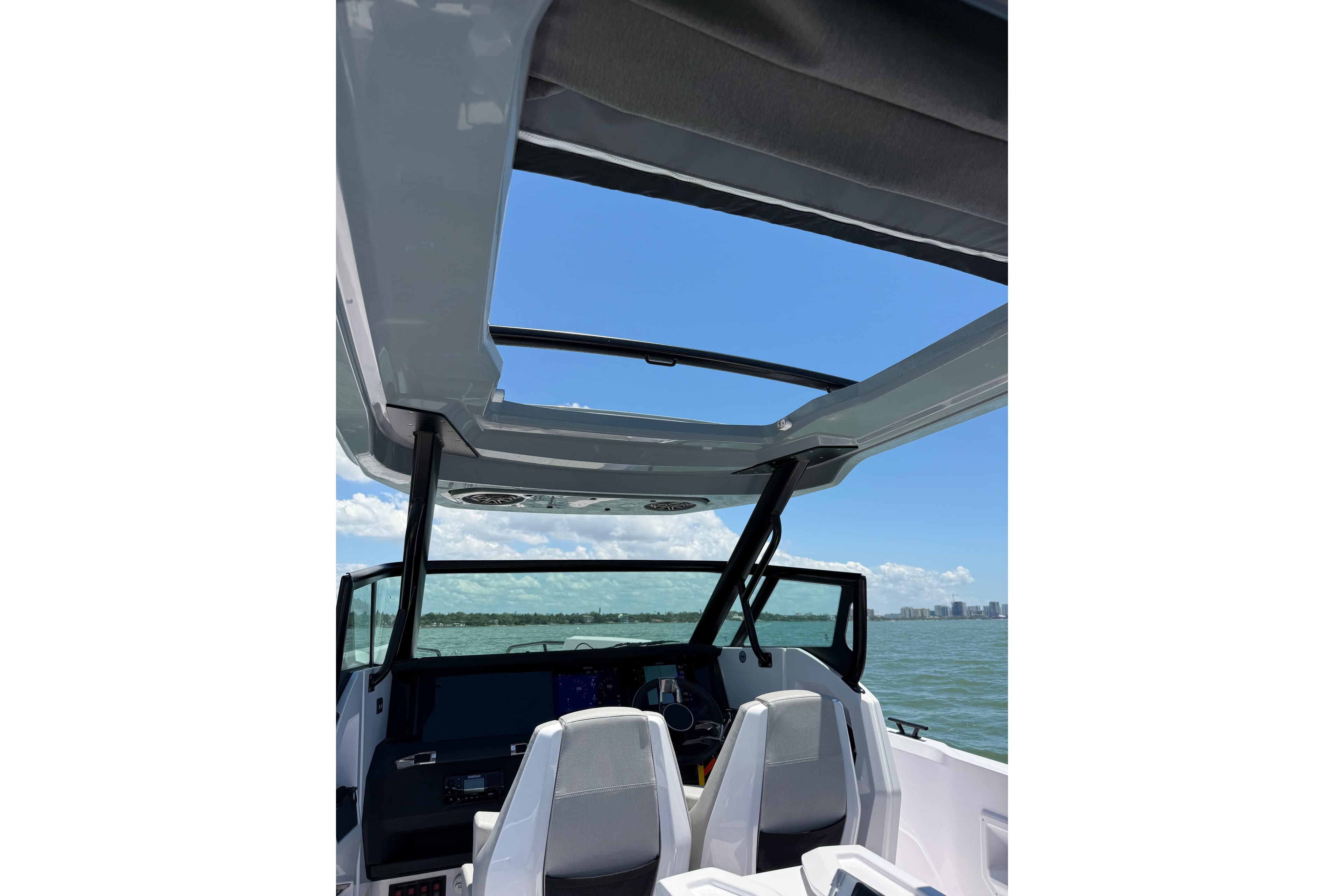 2025 Axopar 29 Sun-Top boat interior with open roof, overlooking ocean and skyline.
