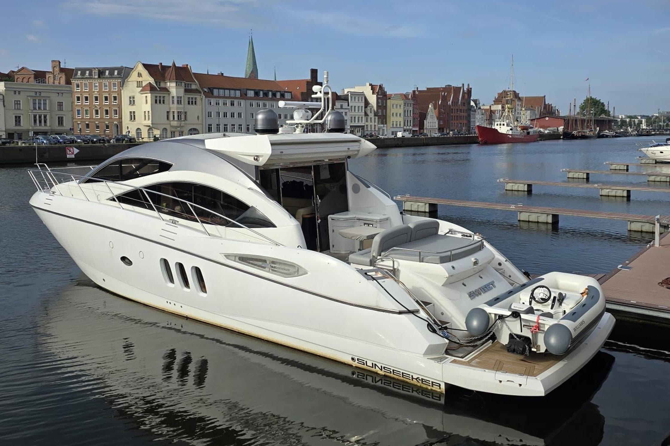 2008 Sunseeker Predator 52 yacht docked in a scenic harbor with historic buildings.