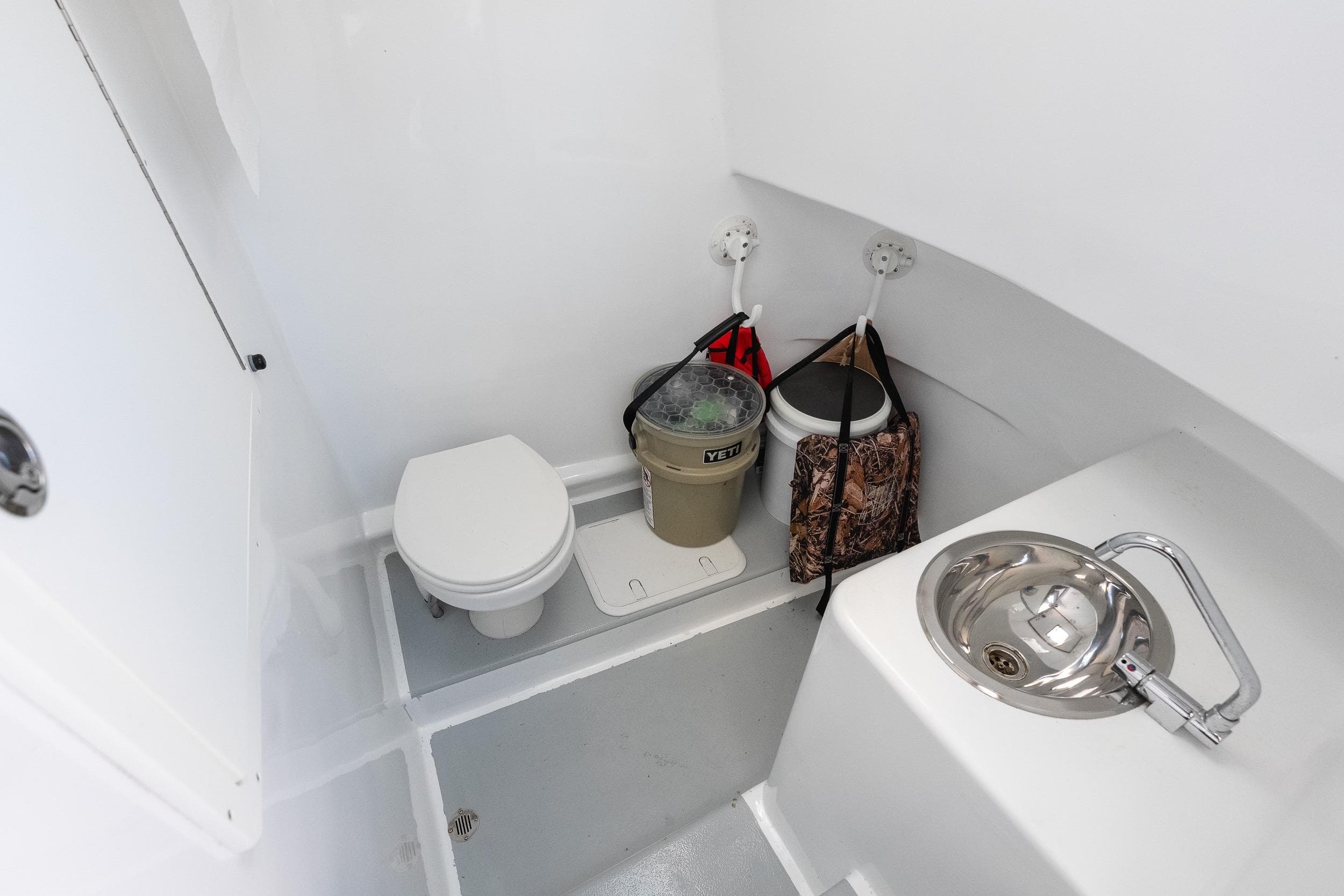 Compact bathroom in 2020 Custom Redfinn 31 boat with toilet and stainless steel sink.
