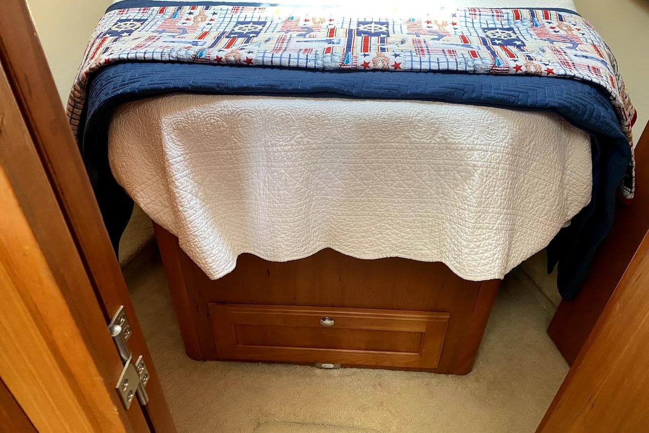 Cozy cabin bed in 2005 Mainship 34 Trawler with nautical-themed quilt.