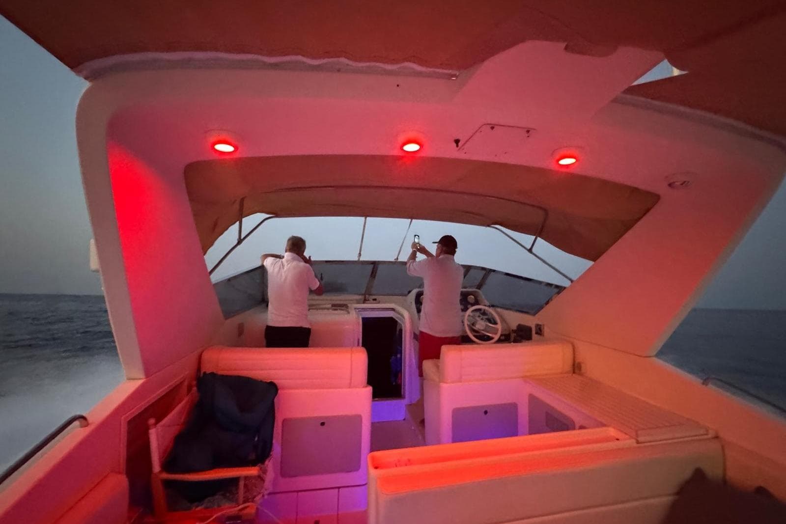 1989 Riva 43' Tropicana yacht interior with red lighting, two people navigating at dusk.