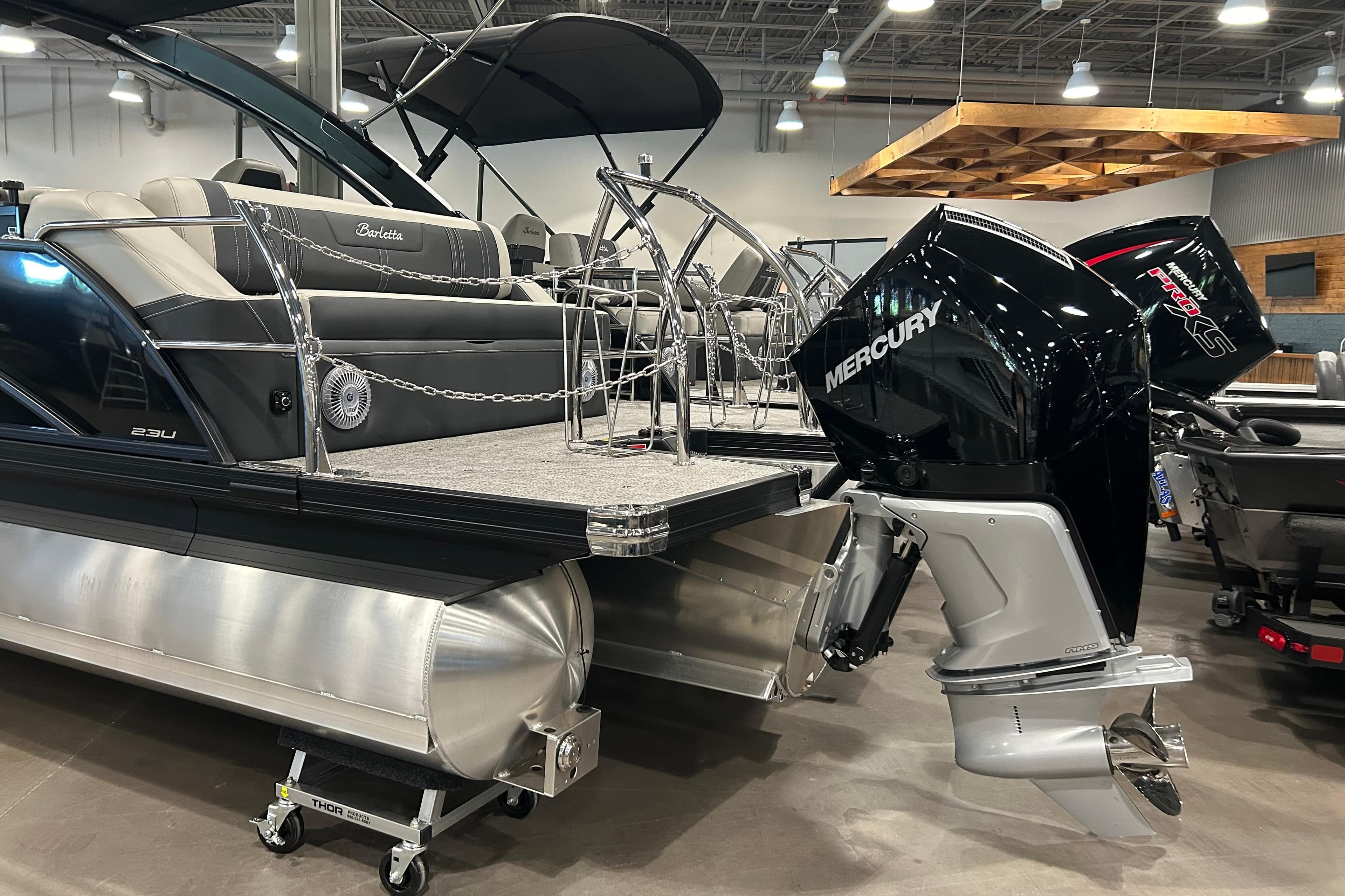 2026 Barletta Corsa 23UA pontoon boat with Mercury outboard engine in showroom.