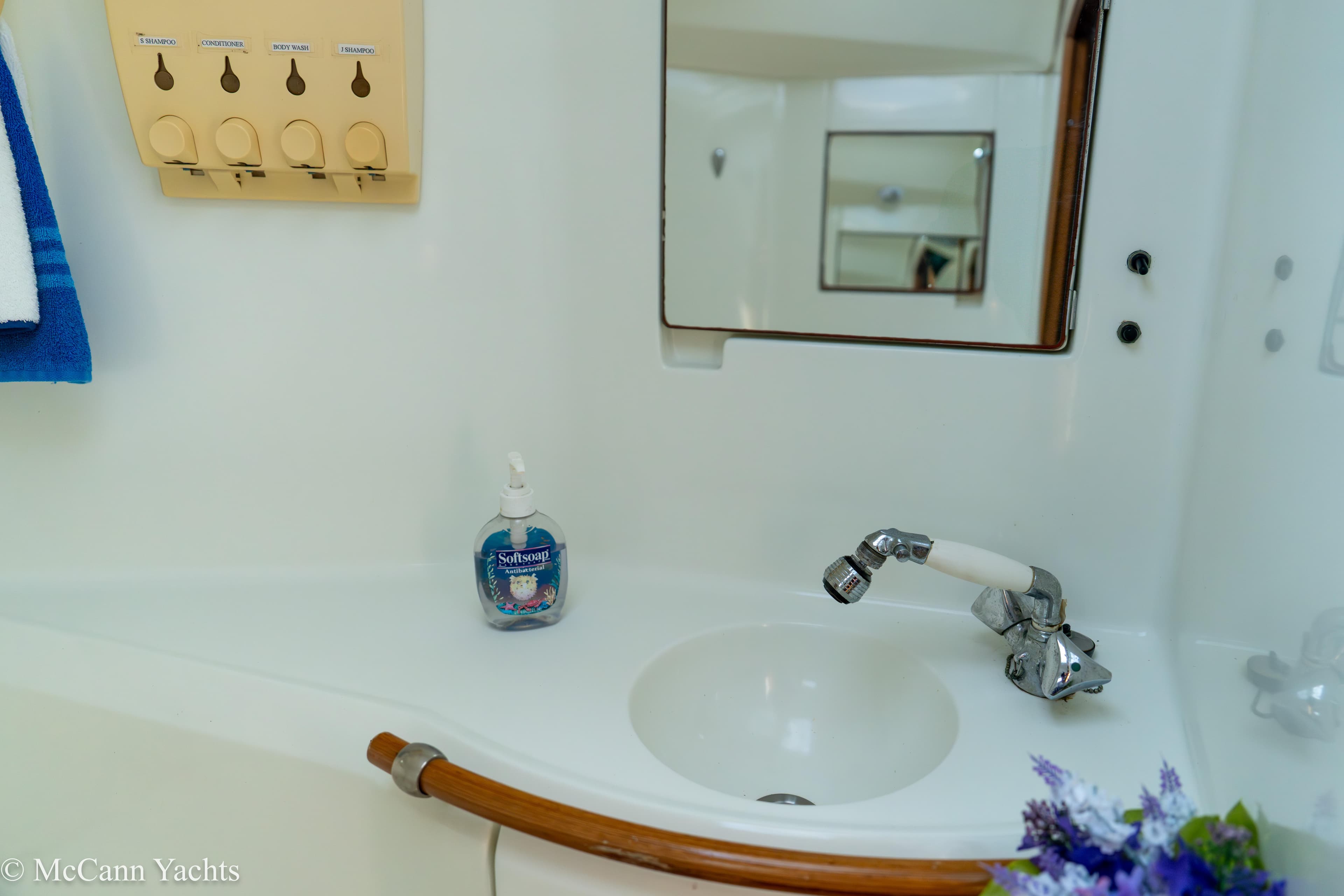 Bathroom sink area on a 1999 Beneteau 411 yacht with soap dispenser and mirror.