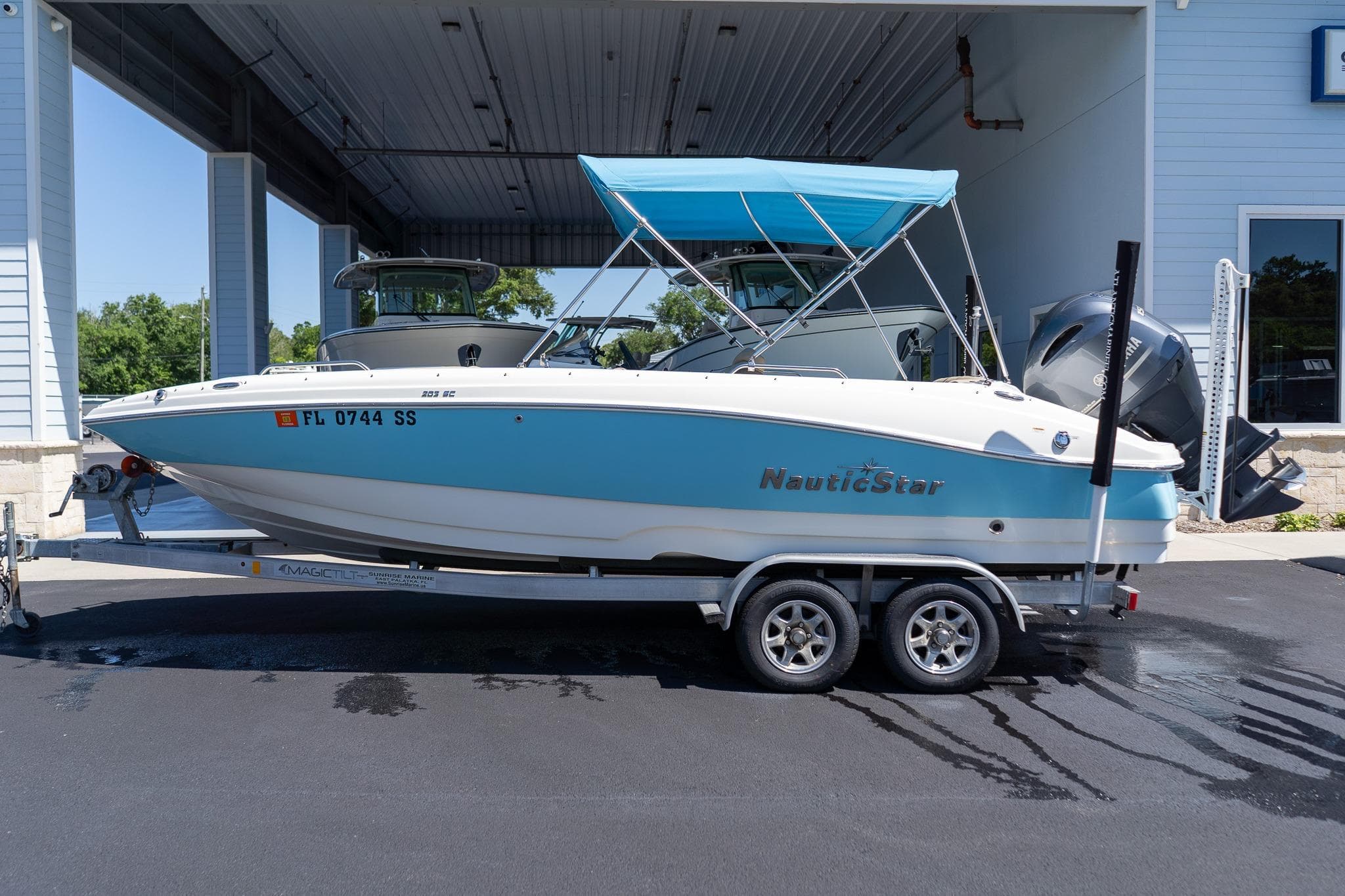 2020 NauticStar 203 SC boat on trailer with blue canopy, parked outdoors.