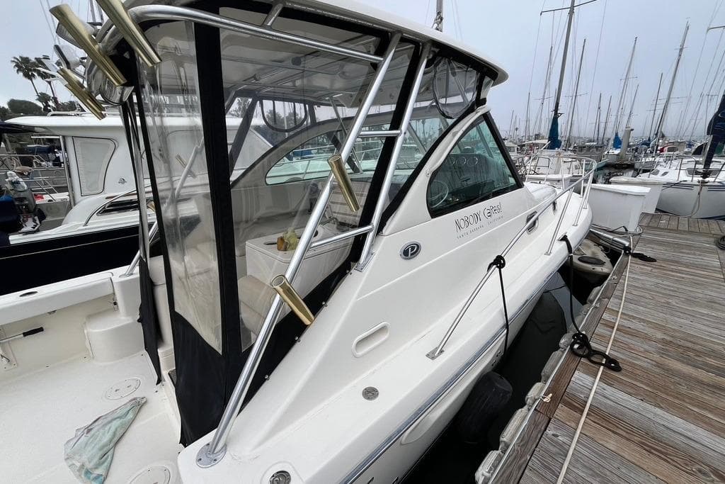 2005 Pursuit 3100 Offshore boat docked at marina, featuring sleek design and fishing rod holders.