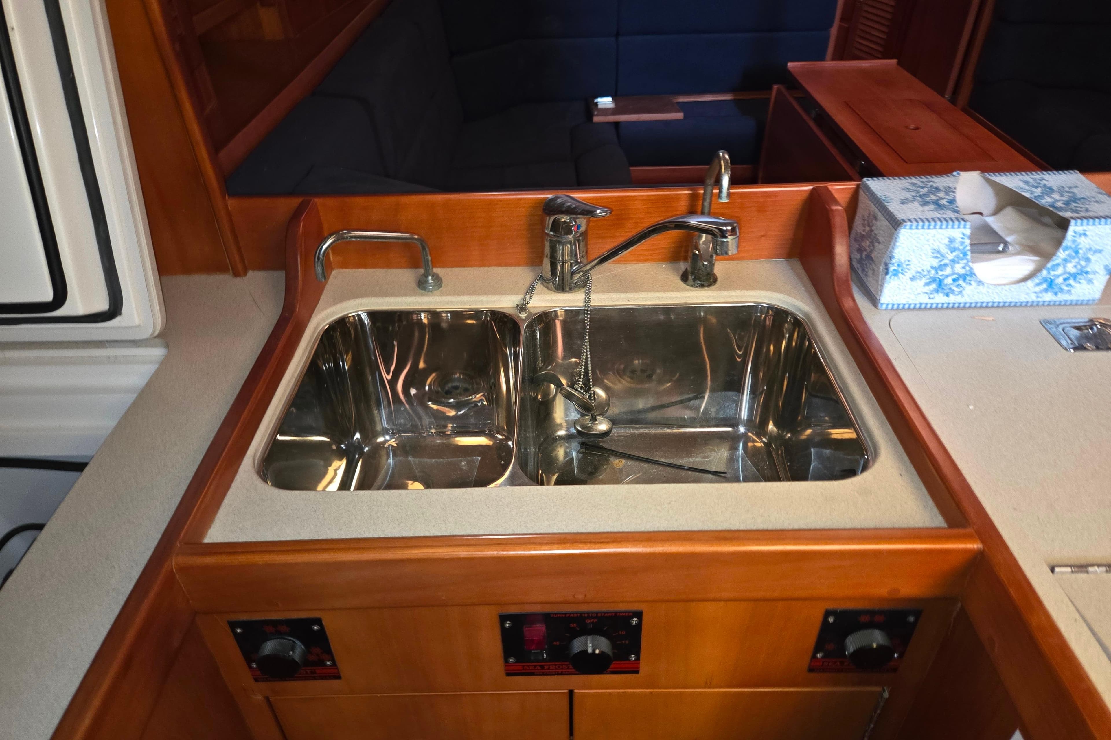 Galley sink in 2000 J Boats J/46 yacht, featuring dual faucets and wooden cabinetry.