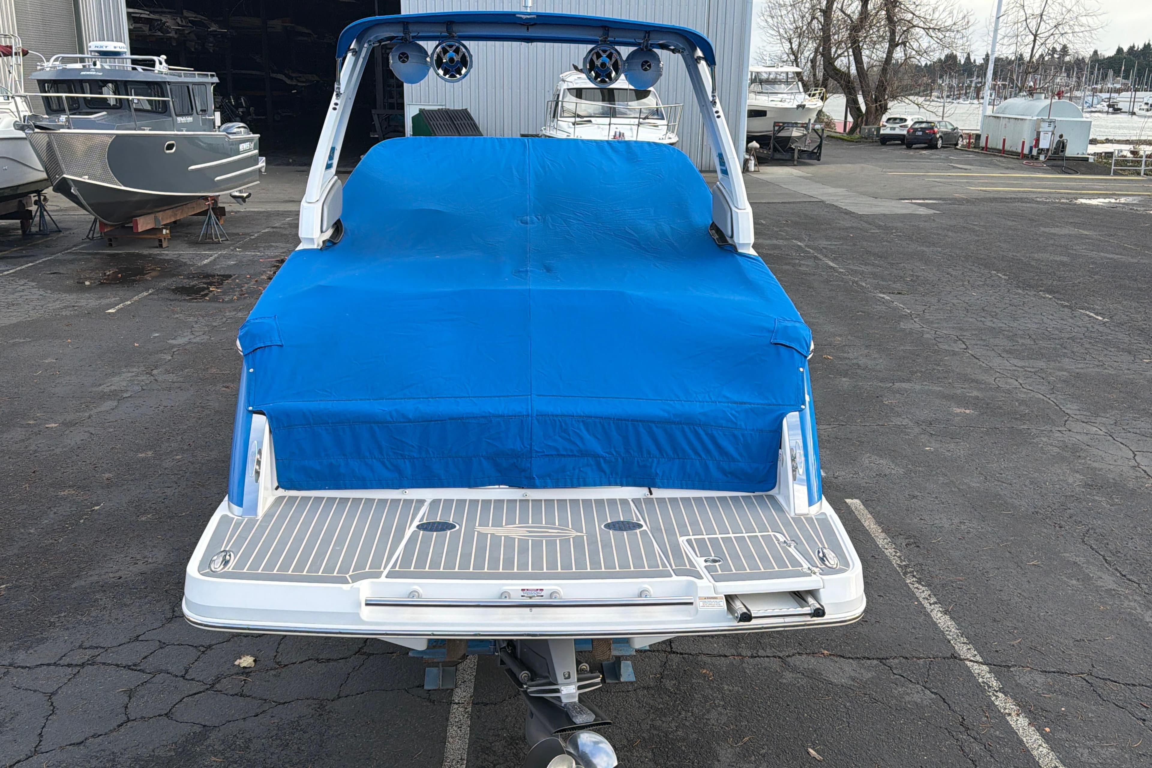 2018 Chaparral 267 SSX boat with blue cover in a marina parking lot.