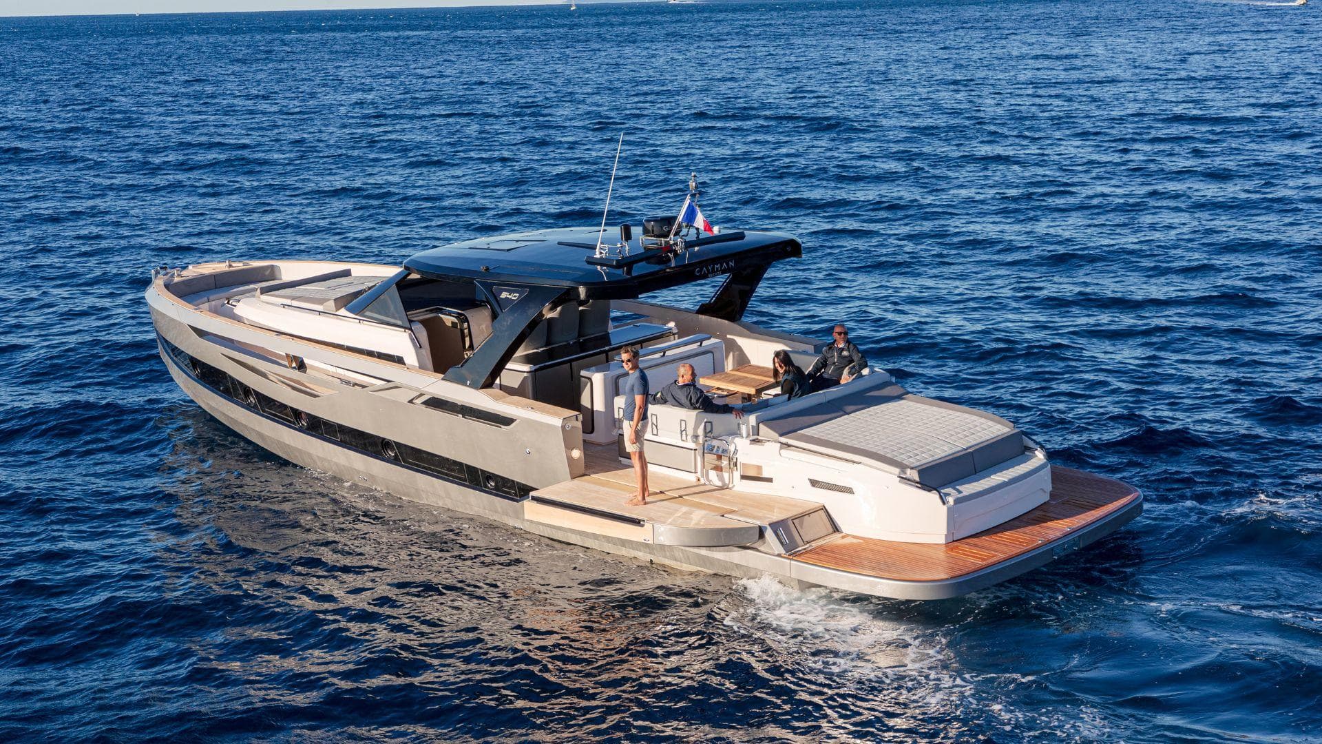 2024 Cayman Yachts 540 wa cruising on open sea, showcasing luxury design and spacious deck.