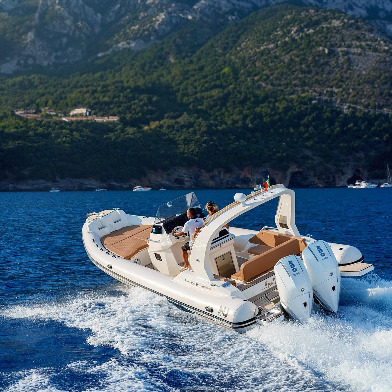 2025 Nuova Jolly Prince 30 Exclusive cruising on blue waters with scenic mountain backdrop.