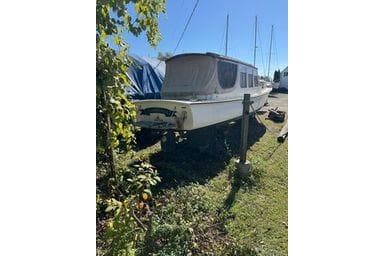 2001 Logan 33 boat on grass, partially covered, with clear blue sky.