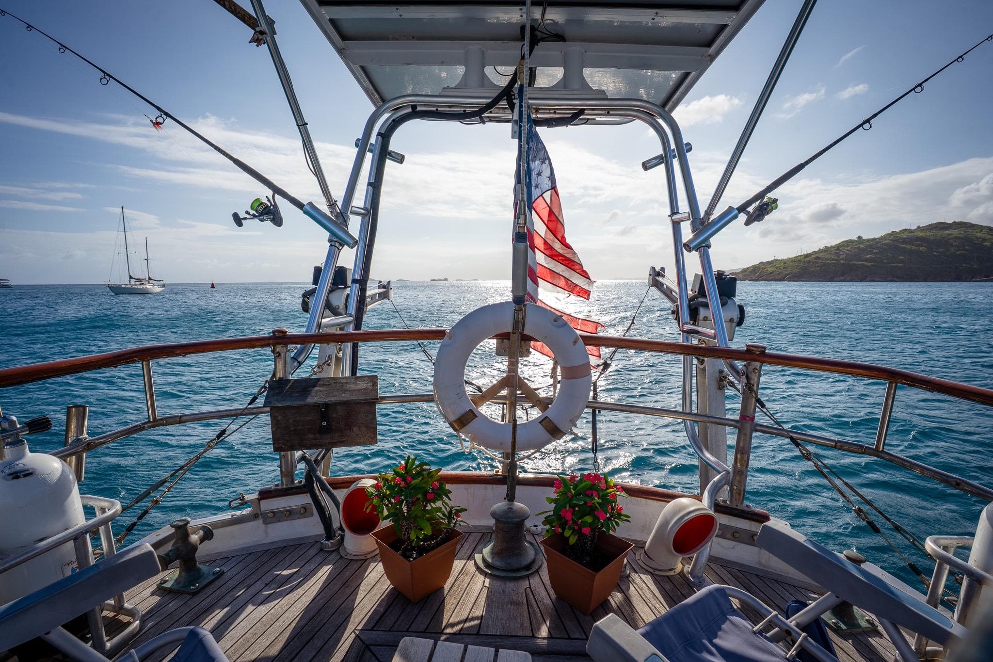 Deck view of 1973 Alan Wright Custom 65 yacht with American flag and ocean backdrop.