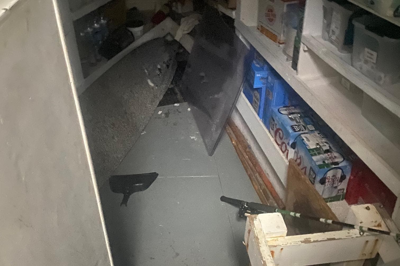 Cluttered storage area with shelves, boxes, and miscellaneous items.