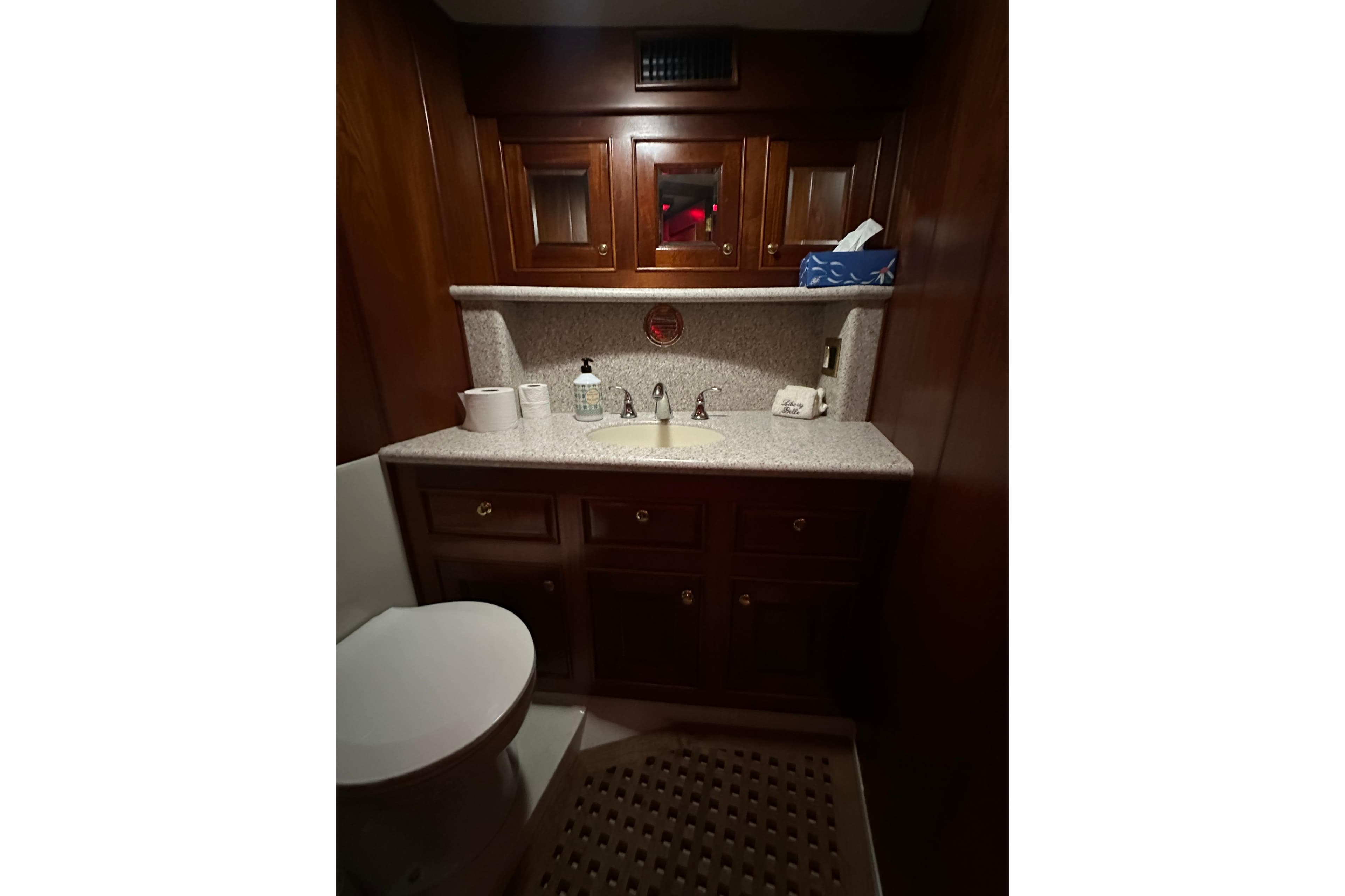 Luxurious bathroom interior of a 1980 Bertram 58 Convertible yacht with wooden cabinetry.