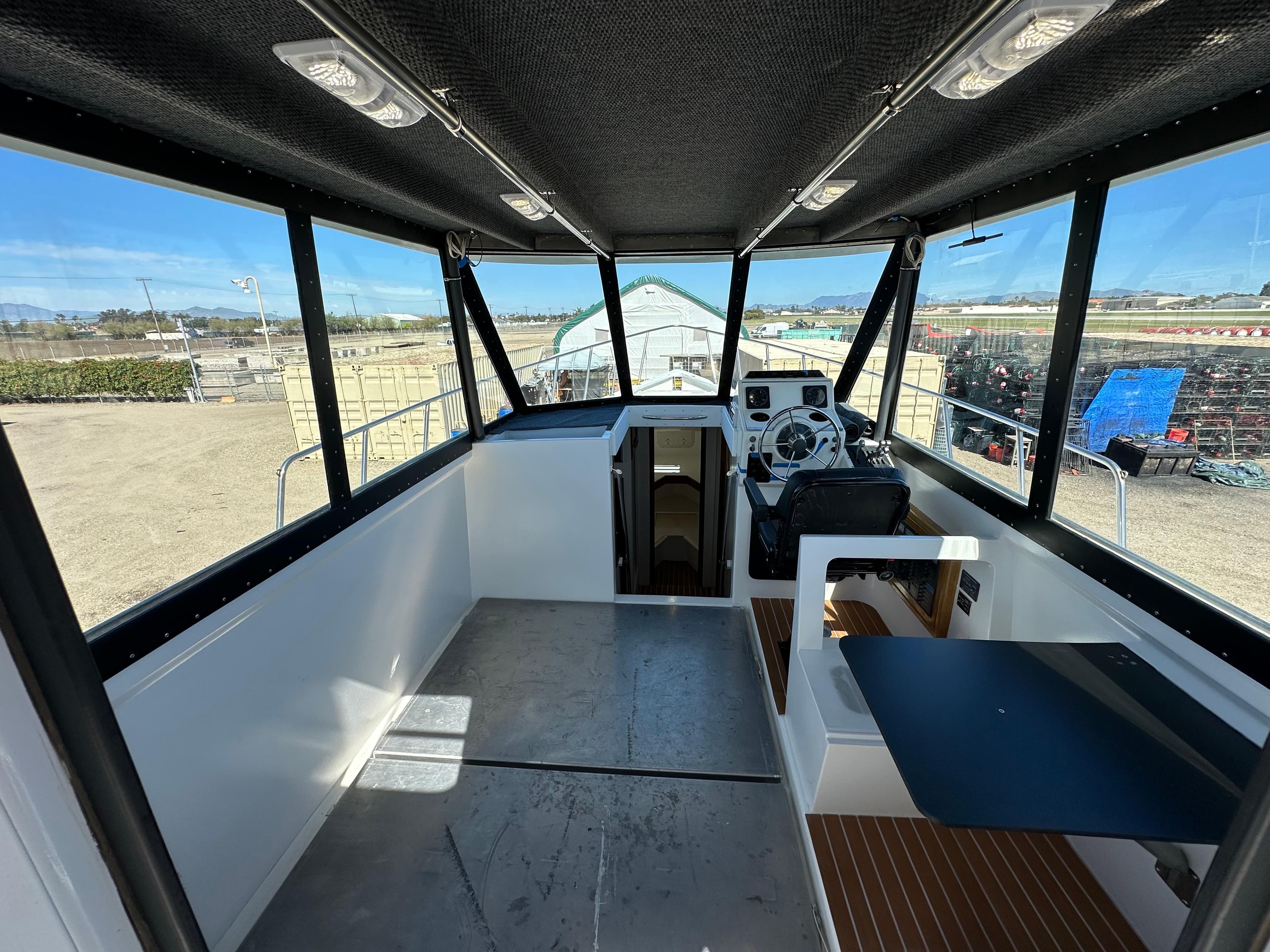 Interior of a 1992 Custom Hueneme Boat Works vessel with steering console and seating area.