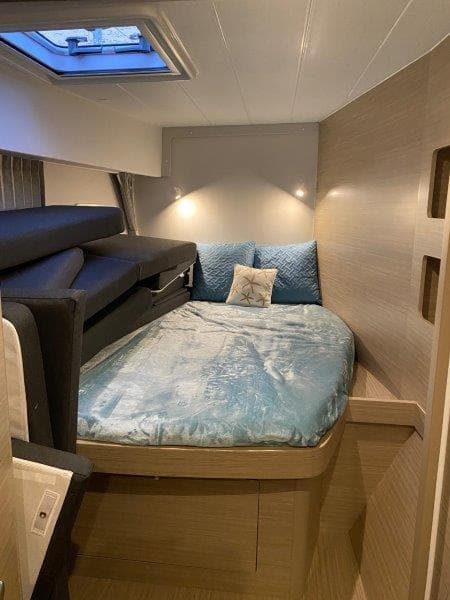 Modern bedroom interior of 2024 Lagoon 42 catamaran with skylight and cozy bedding.